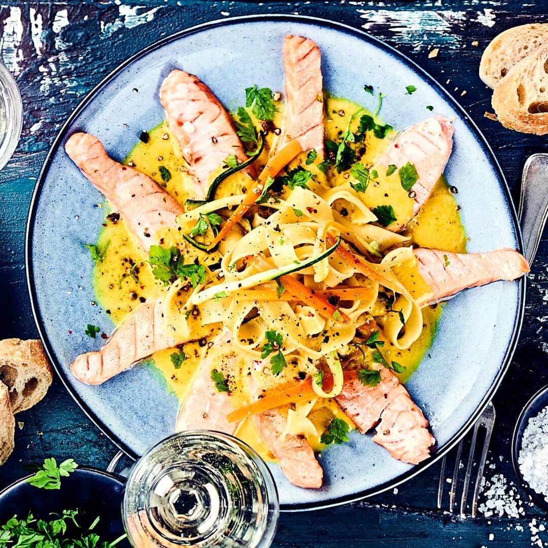 Fisch darf gerne öfters auf den Tisch? Dann backen Sie mit uns ein farbenfrohes Lachsgratin mit sattgelber Safransoße, Gemüsenudeln aus Karotten und Zucchini sowie Pasta.