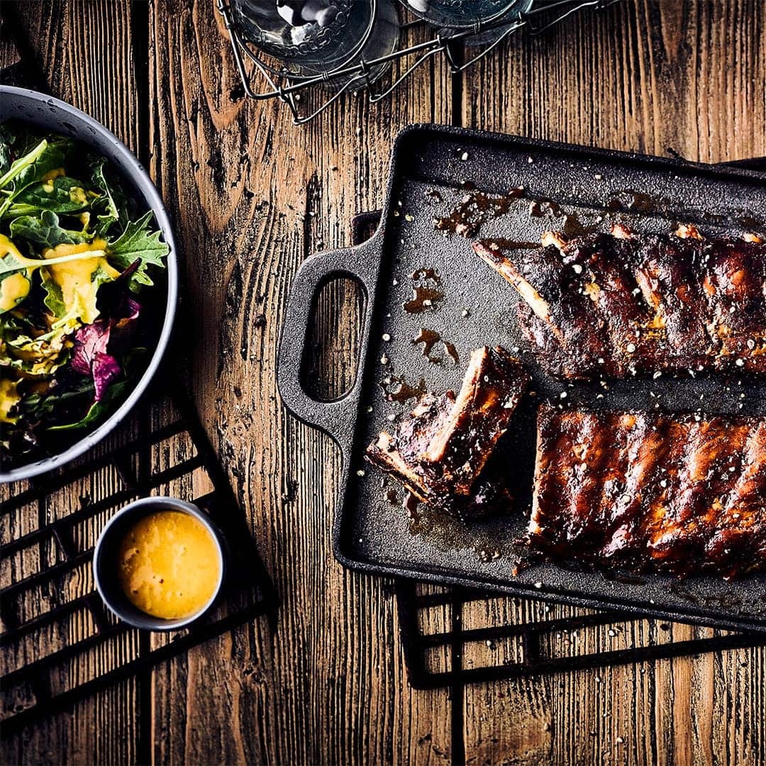 Spareribs werden bei unserem Rezept pikant mariniert und während des Grillens mit Apfelsaft beträufelt. Dazu gibt es einen bunten Blattsalat.
