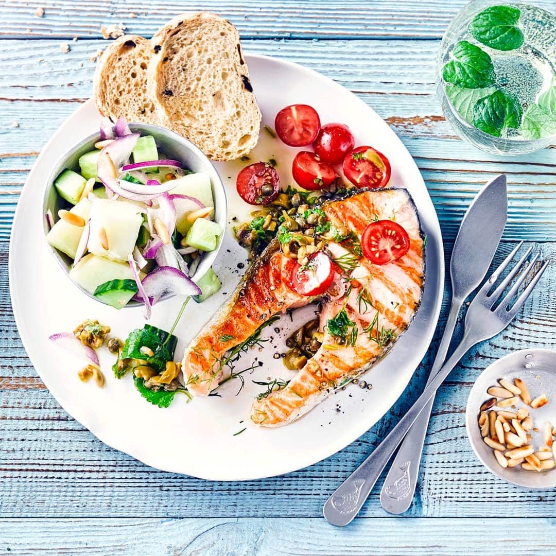 Raffinierte Kombination für Ihren Grill-Abend: Genießen Sie saftiges Lachssteak mit würziger Olivenvinaigrette und dazu einen frischen Gurken-Melonen-Salat!