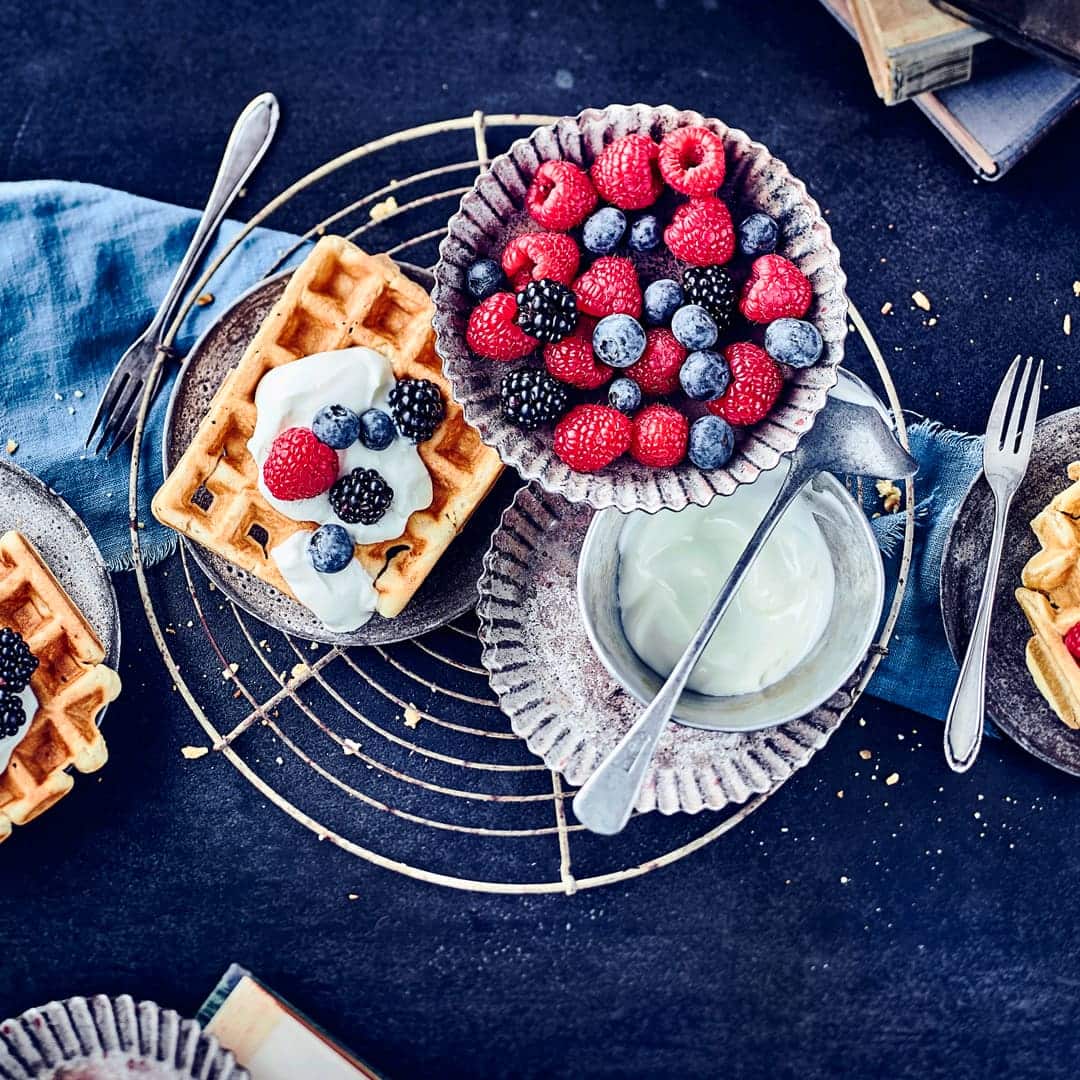 Da läuft einem glatt das Wasser im Mund zusammen! Die Buttermilchwaffeln sind besonders fluffig und werden mit selbstgemachter Vanille-Quark-Creme und ganz viel frischem Obst serviert!