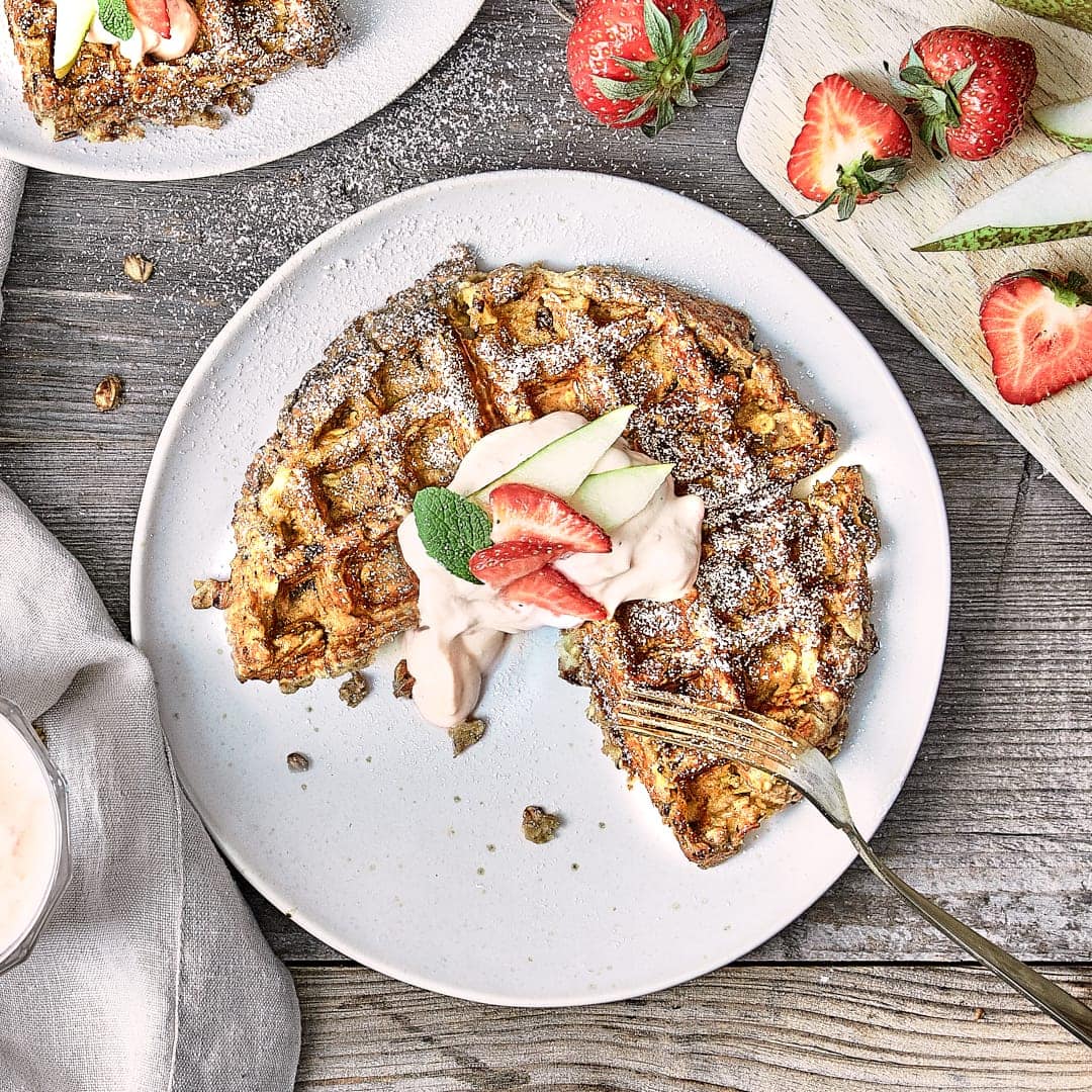 Fruchtig und süß: Probieren Sie unsere kernigen Birnenwaffeln mit getrockneten Pflaumen und Haferflocken an einer Vanillecreme mit Zimt und frischen Erdbeeren!
