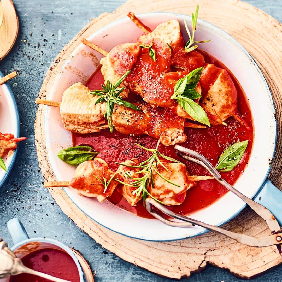 Genuss pur: unsere marinierten Hähnchenspieße mit saftigem Hähnchenbrustfilet in einer selbstgemachten Marinade für einen tollen Geschmack -  dazu eine würzige Tomatensauce und frische Kräuter.