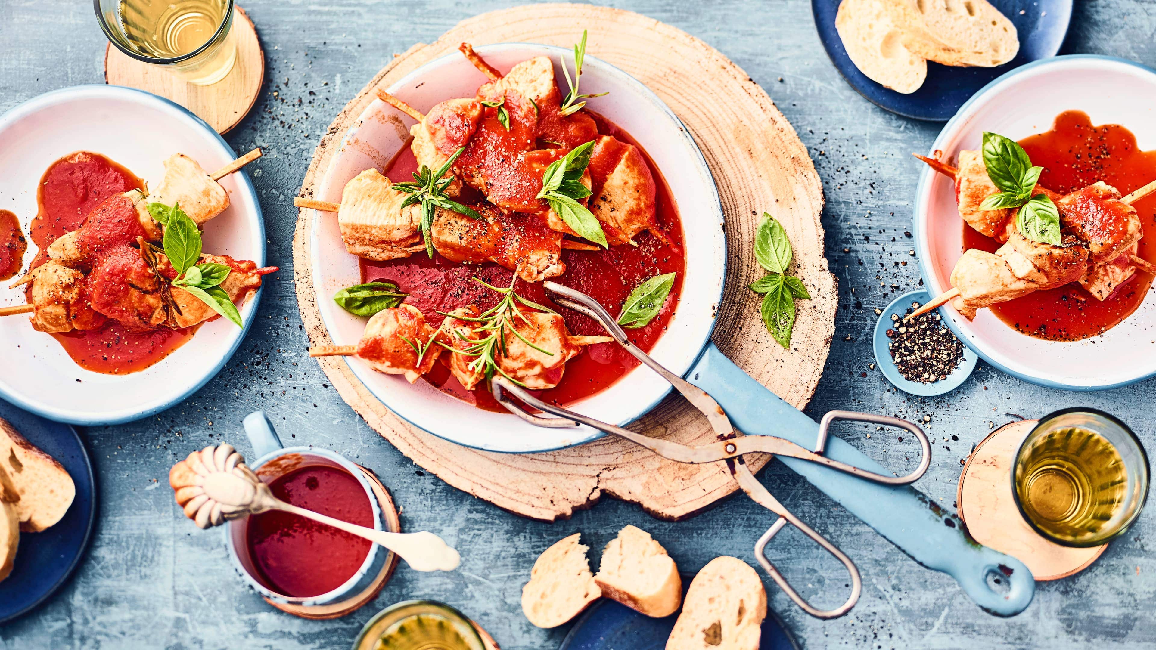Marinierte Hähnchenspieße Genuss pur: unsere marinierten Hähnchenspieße mit saftigem Hähnchenbrustfilet in einer selbstgemachten Marinade für einen tollen Geschmack - dazu eine würzige Tomatensauce und frische Kräuter.