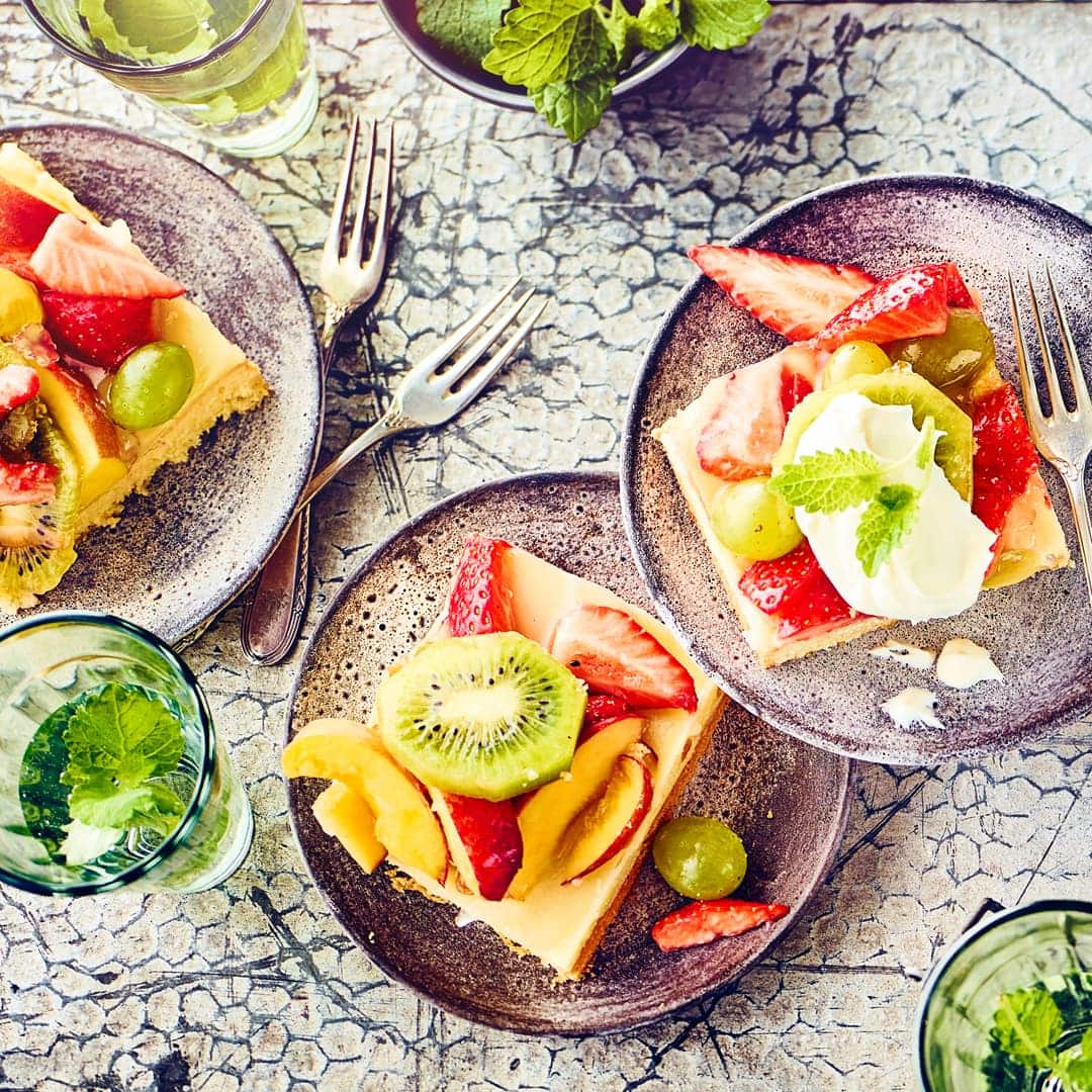 Luftiger Rührteig vom Blech mit vielen gemischten Früchten belegt und einem klaren Tortenguss.