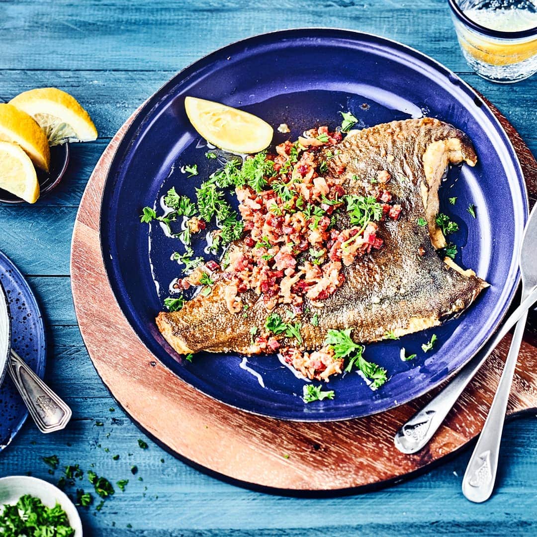 Typisches Norddeutsches Rezept gesucht? Dann ist die Finkenwerder-Scholle mit Speck genau das richtige. Die in Mehl gewendete Scholle wird in der Pfanne gebraten und mit Speckwürfeln getoppt.