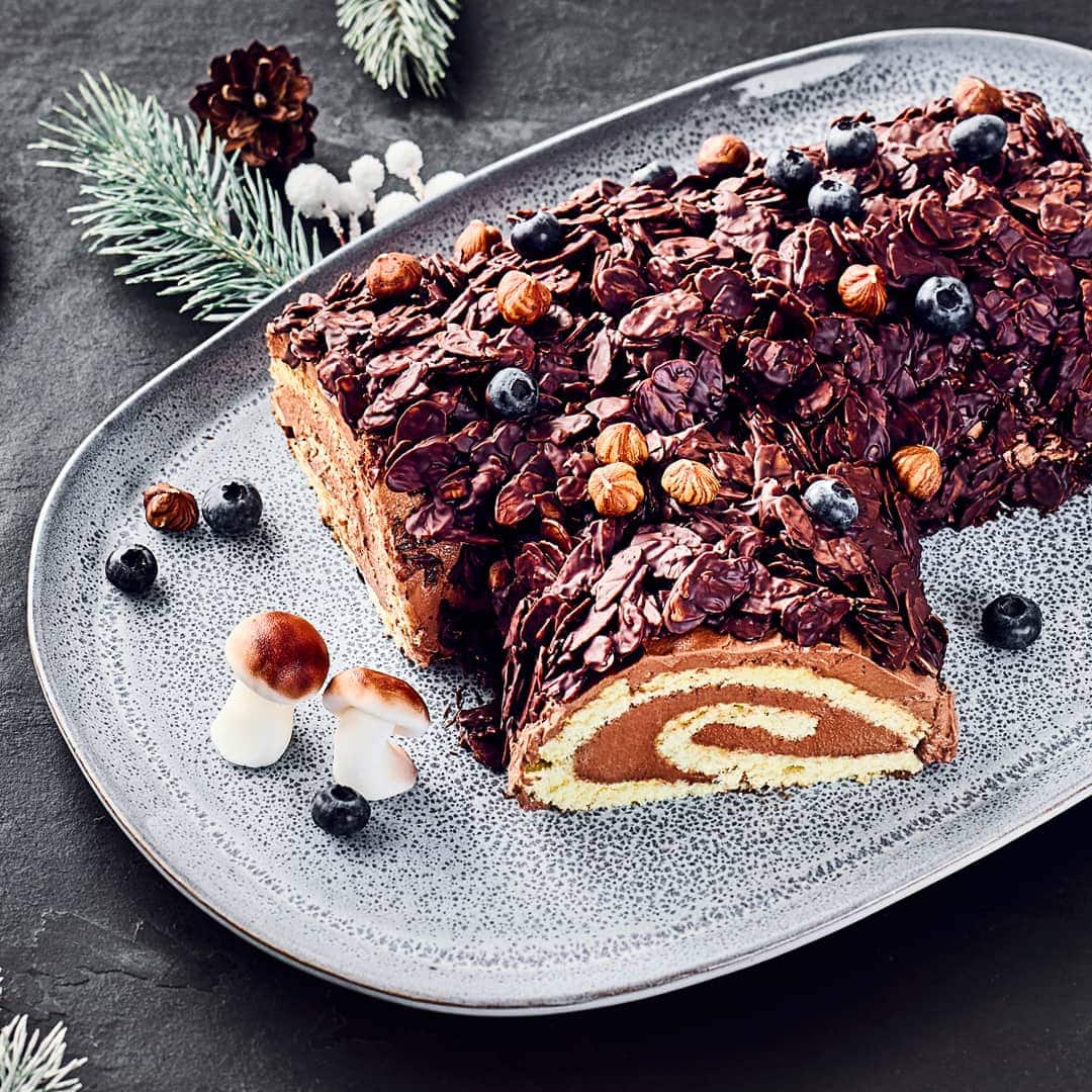 Der Name sagt es aus: Unser Kuchen sieht aus wie ein Baumstamm, schmeckt aber zart schmelzend nach Schokoladen-Buttercreme und Biskuitteig. Der Kuchen kommt aus Frankreich und ist dort als Bûche de Noël bekannt.