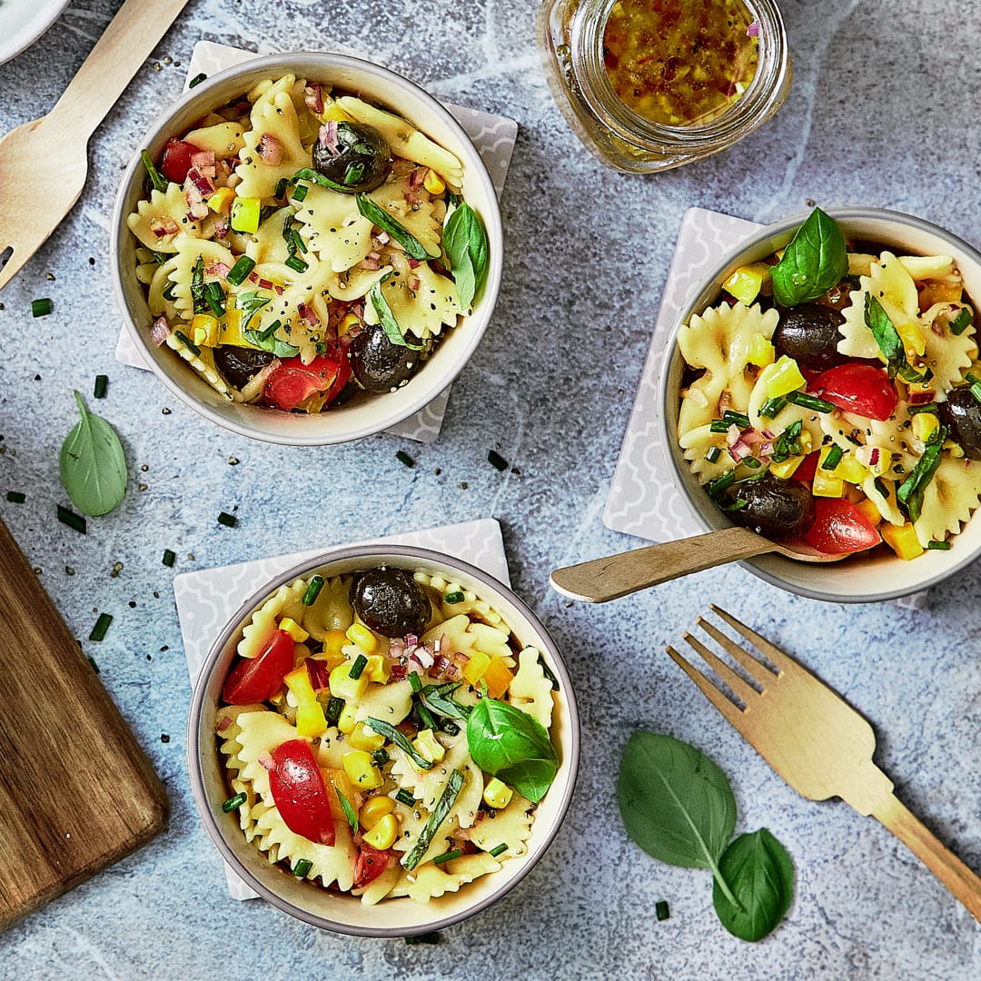 Unser mediterraner Nudelsalat mit Tomaten, Paprika, Mais und Oliven bringt die intensiven Aromen der Mittelmeerküche auf Ihren Teller.