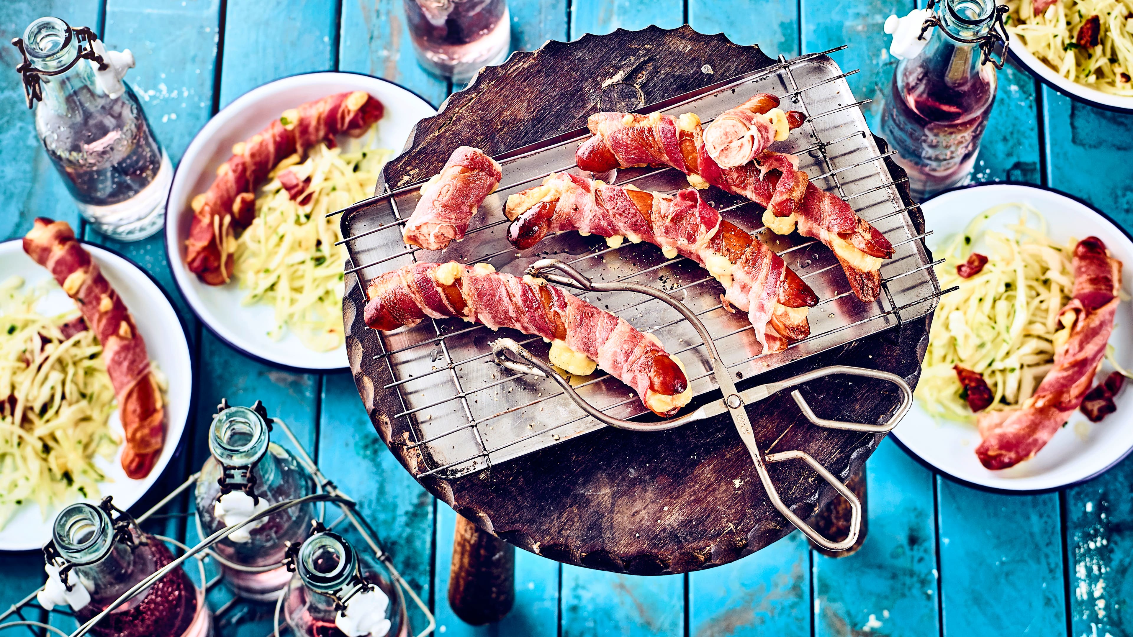 Berner Würstel vom Grill Wiener Würstchen aufgeschnitten, mit Käse gefüllt und mit Frühstücksspeck umwickelt serviert mit Schweizer Speck-Kraut-Salat aus der Schweiz.