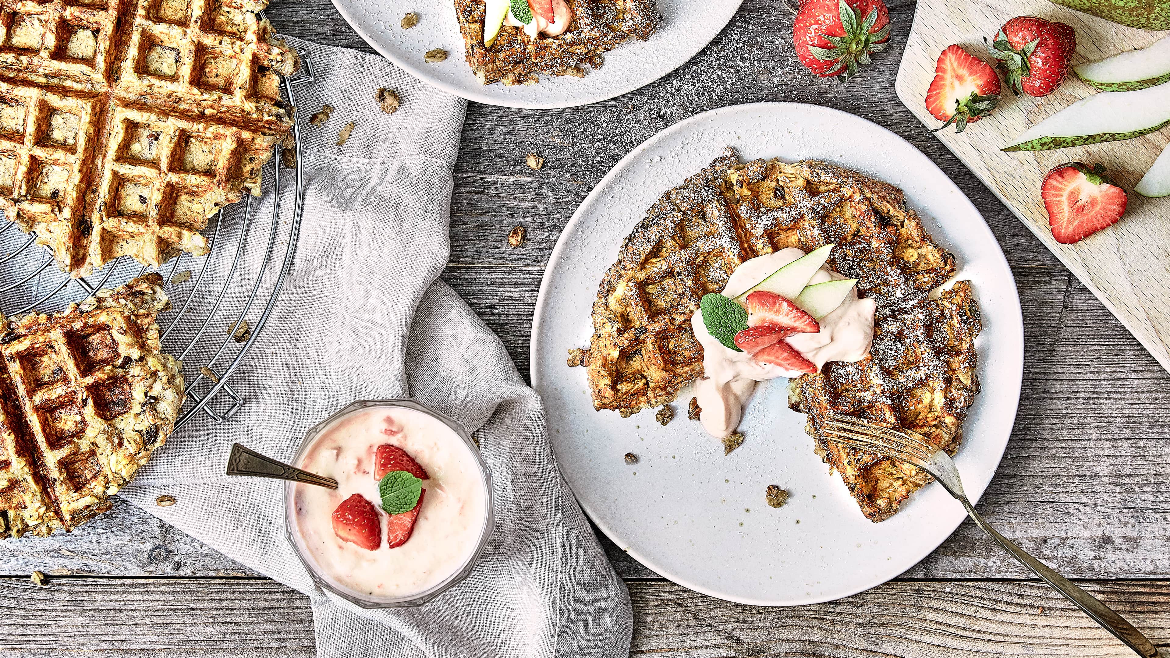 Fruchtig und süß: Probieren Sie unsere kernigen Birnenwaffeln mit getrockneten Pflaumen und Haferflocken an einer Vanillecreme mit Zimt und frischen Erdbeeren!