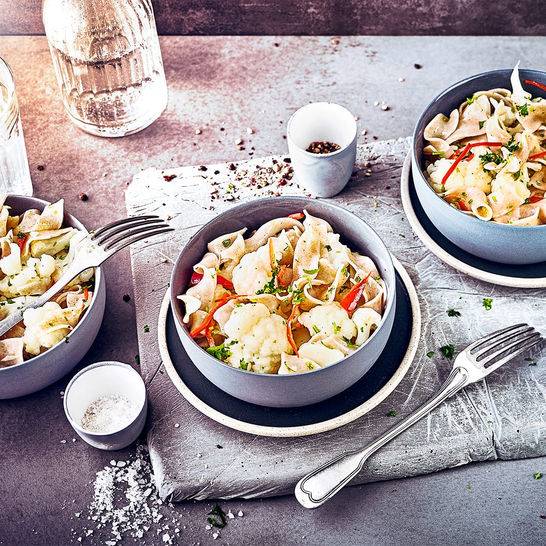Fein geschnittener Knoblauch, Petersilie und gedünstete Zwiebeln verleihen unseren Vollkornnudeln mit Blumenkohl und Chili zusätzlich eine würzig Note.