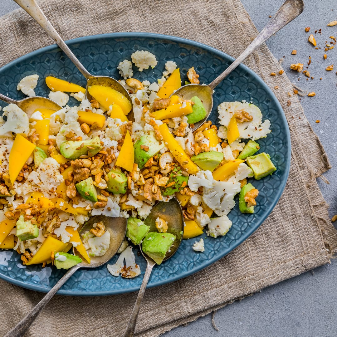 Blumenkohl ist ganz schön vielseitig, und darum machen wir daraus diesen leckeren Blumenkohl-Salat mit Mango, Avocado und einem Nuss-Topping.