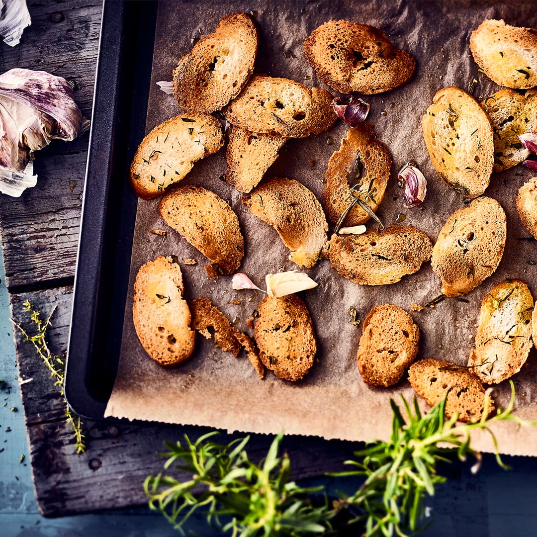 Ideal als kleiner Snack vor der Vorspeise oder als Chips-Ersatz zum Knabbern: Selbstgemachte Brotchips mit frischen Kräutern und Knoblauch.