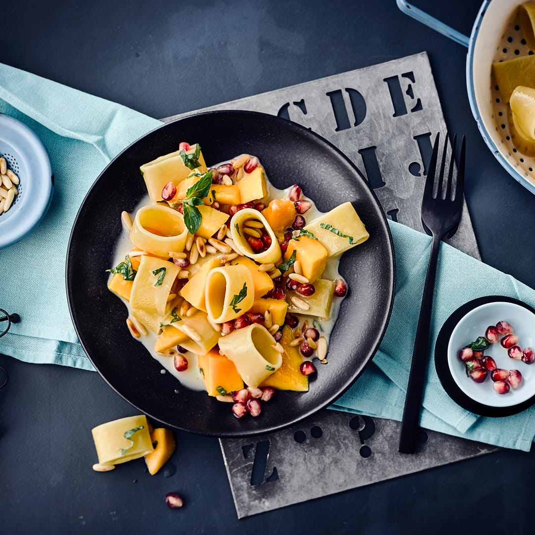 Italienische Calamarata mit Mango, Pinienkernen und Minze. Mit Kokosmilch bekommen die dicken Nudeln einen leicht orientalischen Geschmack und die Soße wird herrlich cremig.