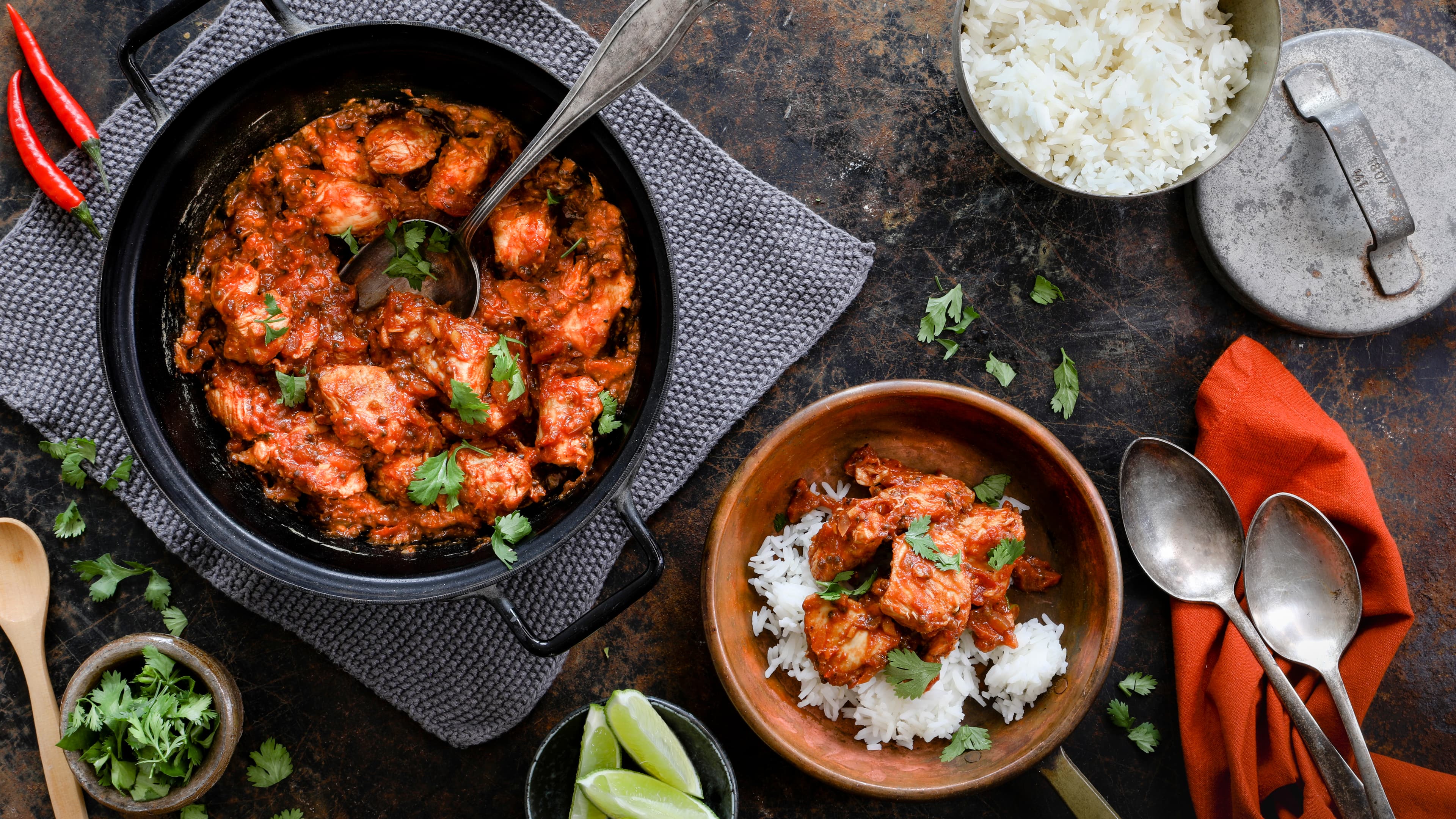 Rezept für indisches Chicken Tikka Masala Ein Topf mit Hähnchen in einer Tomatensauce, getoppt mit Koriander, daneben eine Schale mit dem tomatigen Hähnchen und Reis
