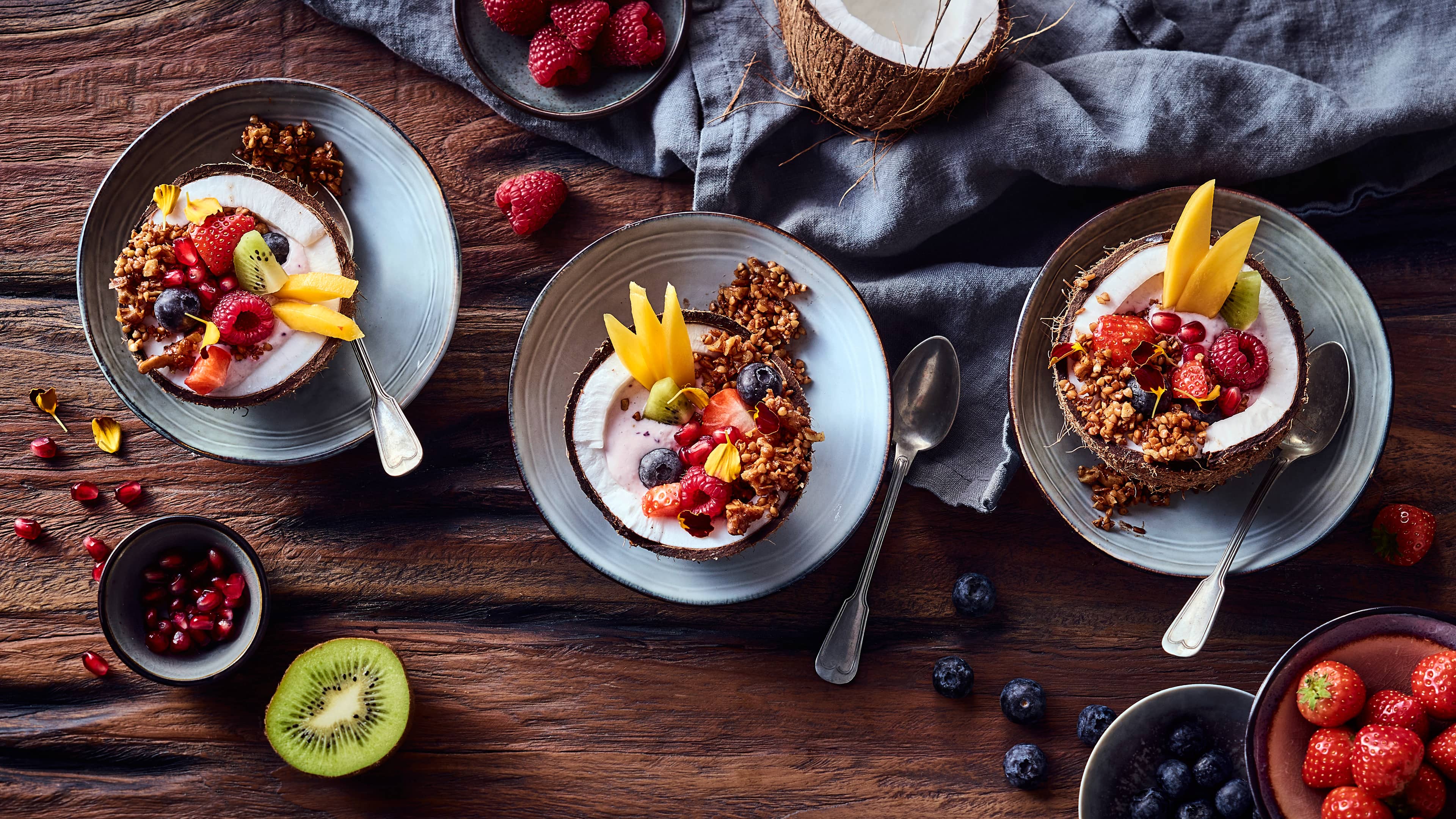 Coconut Bowl Fruchtige Frühstücks Bowl mit knusprigem Buchweizen-Granola, angerichtet in Kokosnusshälften.