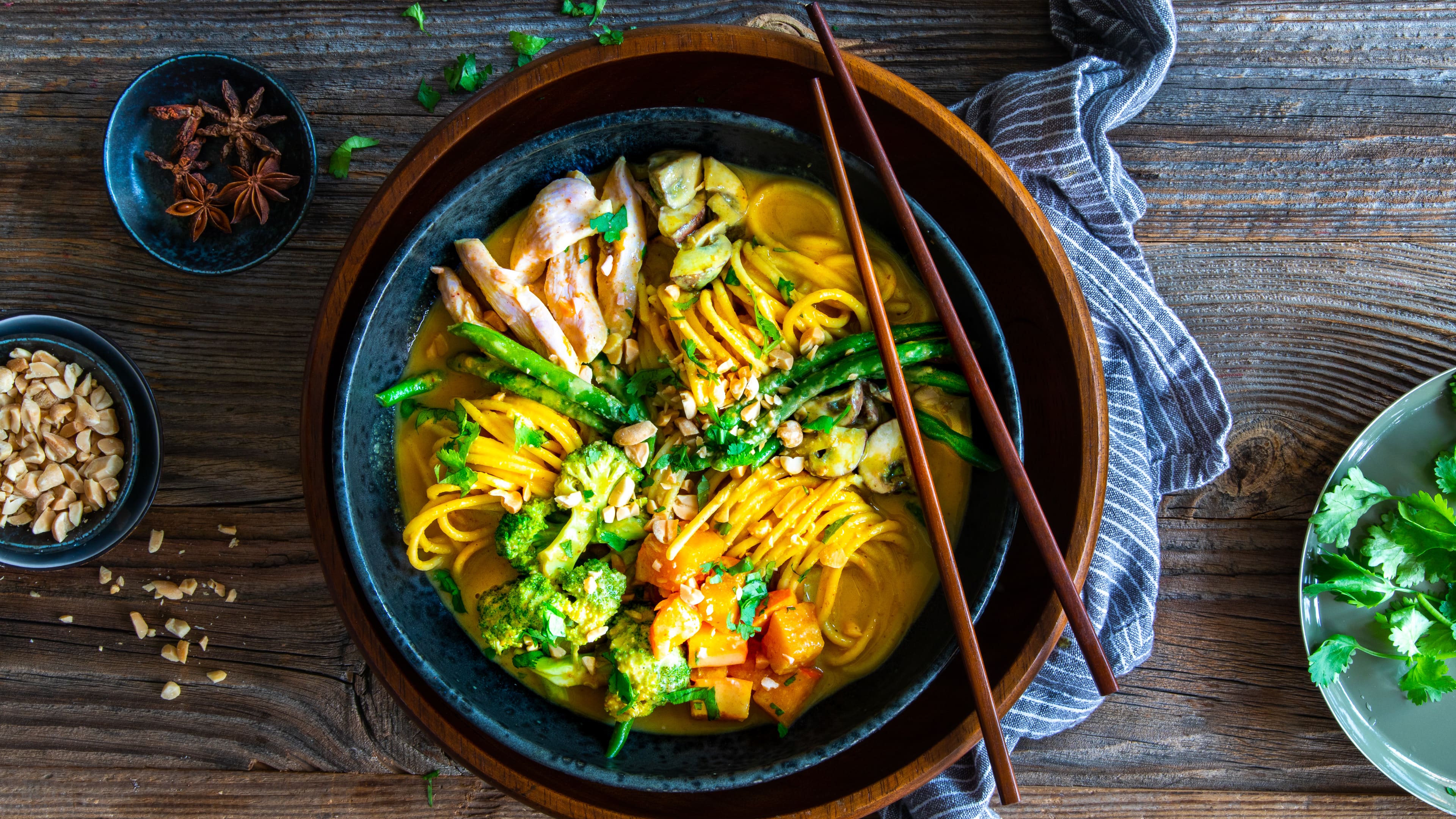 Alles aus einer Schüssel: In unserer Curry-Nudel-Bowln finden Sie Nudeln mit Hähnchenbrust, Brokkoli, Pilzen, Kürbis und Koriander in einer cremigen Erdnuss-Kokos-Sauce.