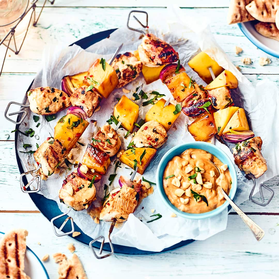 Die zarten Hähnchenspieße mit Erdnusssauce können Sie sowohl auf dem Grill als auch in der Pfanne zubereiten. Probieren Sie jetzt das originelle Rezept mit gegrillter Mango aus!