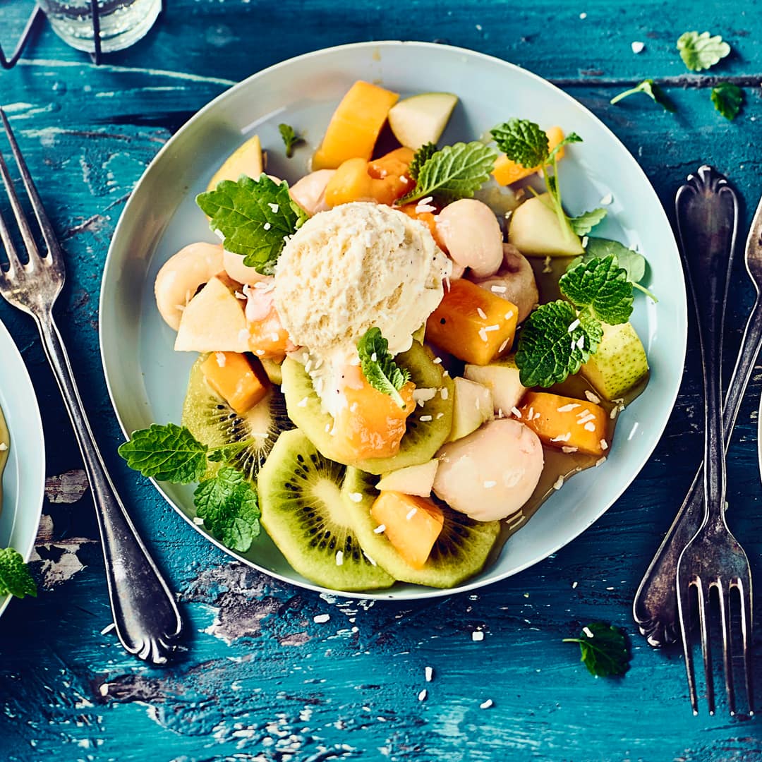 Unser exotischer Fruchtsalat mit Mango, Kiwi, Litschi und Vanilleeis ist ein frischer Genuss, der kleine und große Dessert-Liebhaber begeistert.