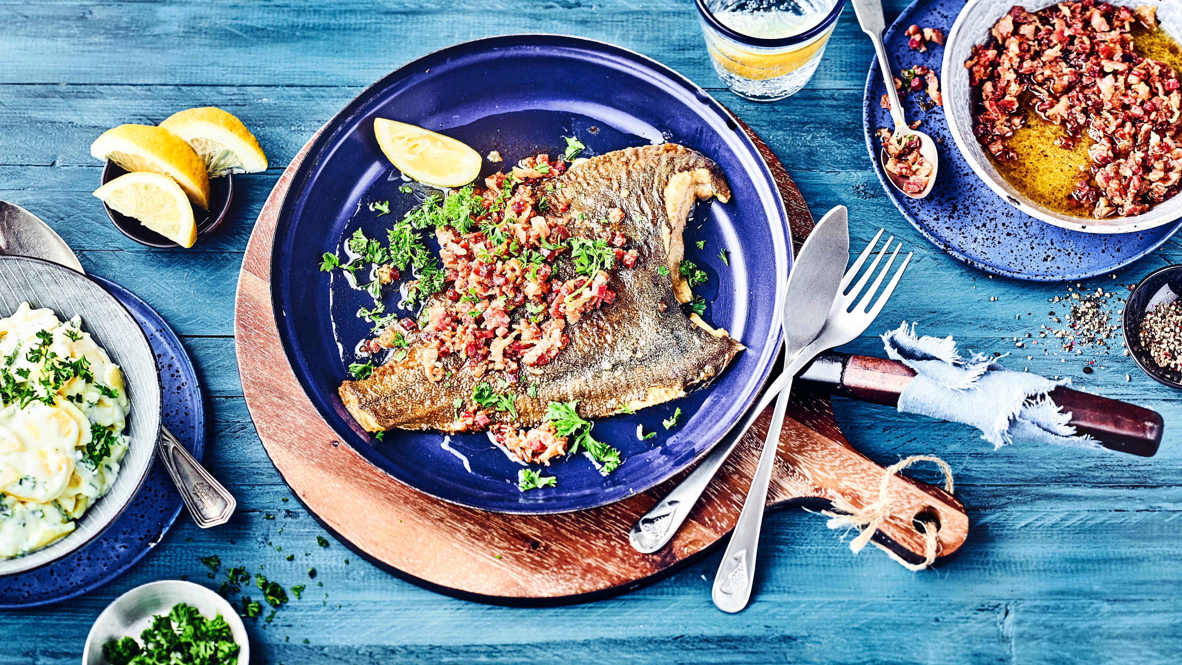 Typisches Norddeutsches Rezept gesucht? Dann ist die Finkenwerder-Scholle mit Speck genau das richtige. Die in Mehl gewendete Scholle wird in der Pfanne gebraten und mit Speckwürfeln getoppt.