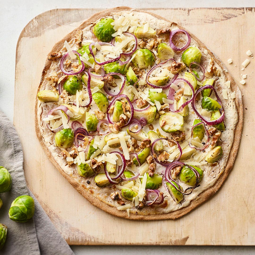 Kochen Sie unser Rezept für Flammkuchen mit Rosenkohl in 40 Minuten nach & servieren Sie Ihren Gästen feines Gemüse mit Walnüssen auf knusprigem Dinkelteig.
