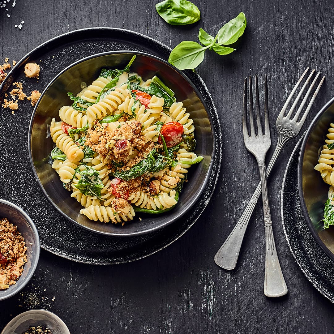 Mediterran und ohne Fleisch: Probieren Sie unser Rezept für Fussili agli spinaci – mit Spinat, Kirschtomaten und gerösteten Haselnussbröseln!