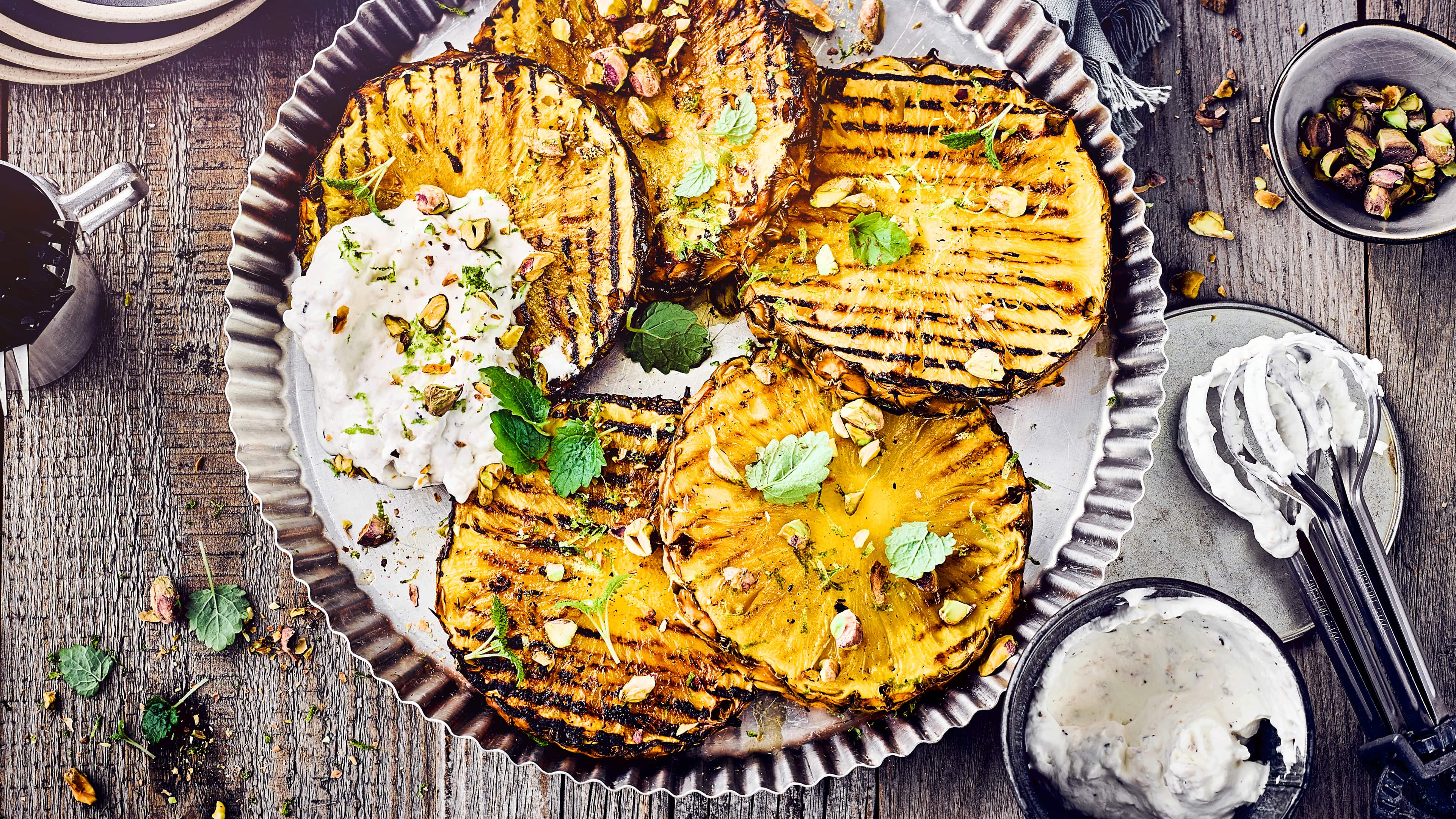Gegrillte Ananasscheiben in Rummarinade, dazu cremiges Kokospüree mit Minze und Pistazien. Ein ganz besonderes Dessert für den Grillabend. Probieren Sie diese Gegrillte Ananas einmal aus!