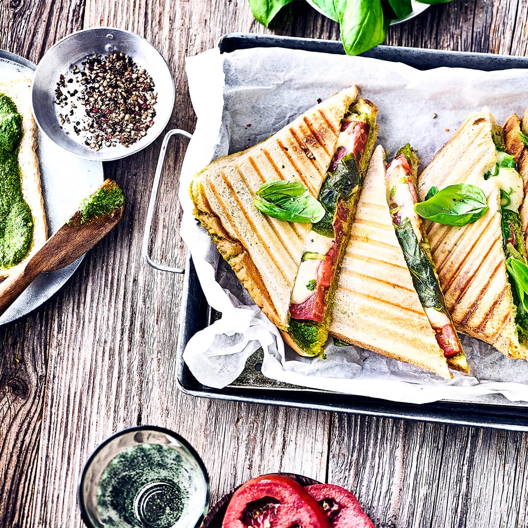 Ruck-Zuck ab in den Sandwichmaker und direkt genießen. Das gegrillte Tomate-Mozzarella-Toast mit selbstgemachtem grünem Pesto ist unsere besonders leckere Variante der leckeren Sandwiches.