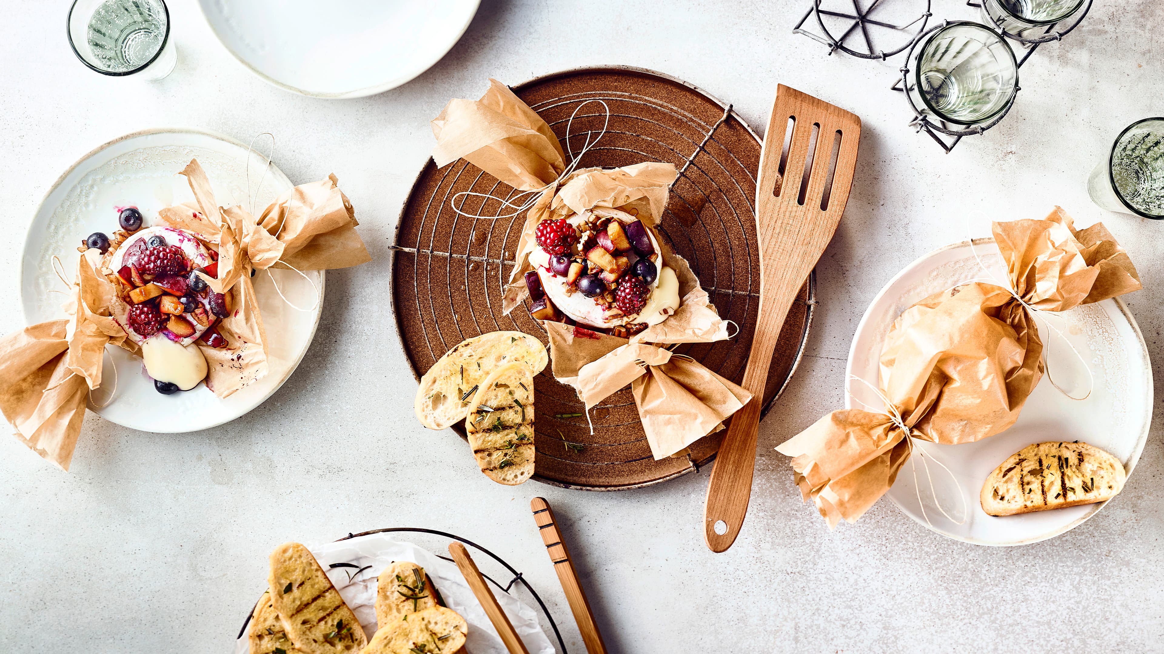 Grillkäse mit Topping Grillkäse deluxe: Wir toppen unseren Grillkäse mit allerlei frischen Beeren und garnieren ihn mit Honig bevor er in mit Öl bepinseltem Backpapier auf dem Grill gegrillt wird.