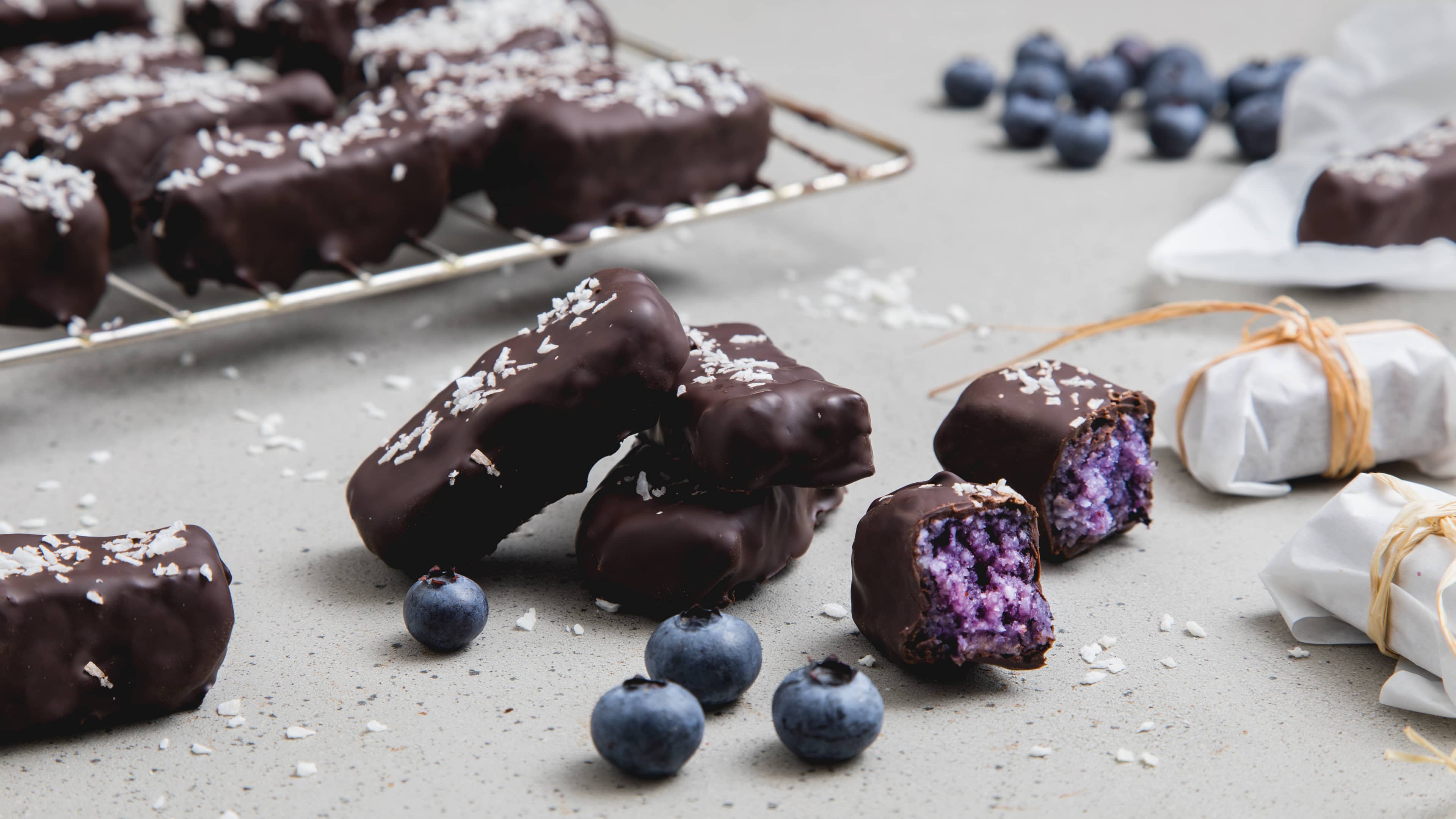 Kokos-Riegel Blaubeeren geben unserem gesunden Kokos-Riegel das fruchtige Etwas, Mandeln, Kokosflocken und Agavendicksaft sorgen für eine süße Füllung.