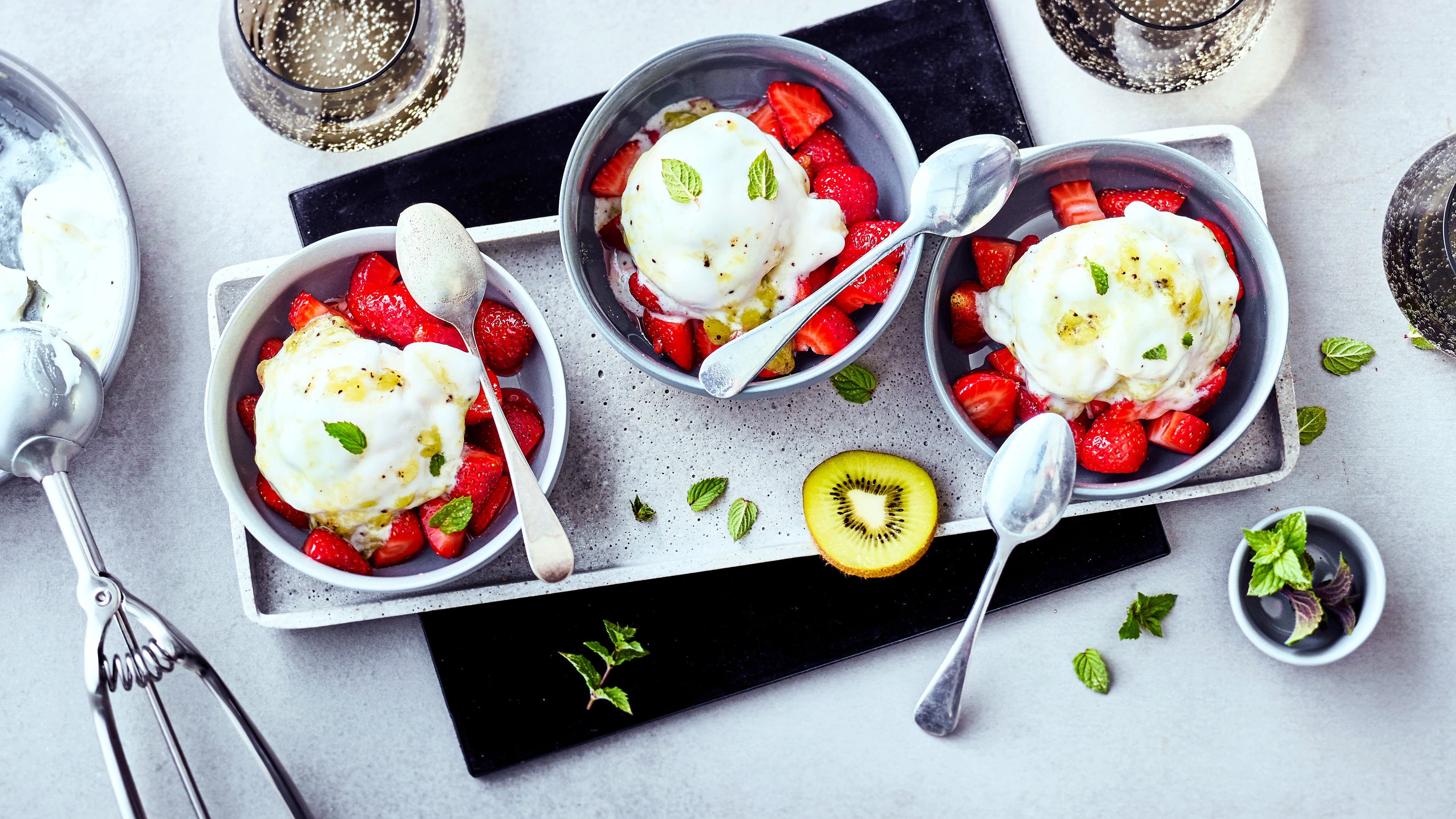 Kiwi-Eis Cremiges Eis aus Kiwis mit marinierten Erdbeeren serviert macht den sommerlichen Genuss herrlich frisch.