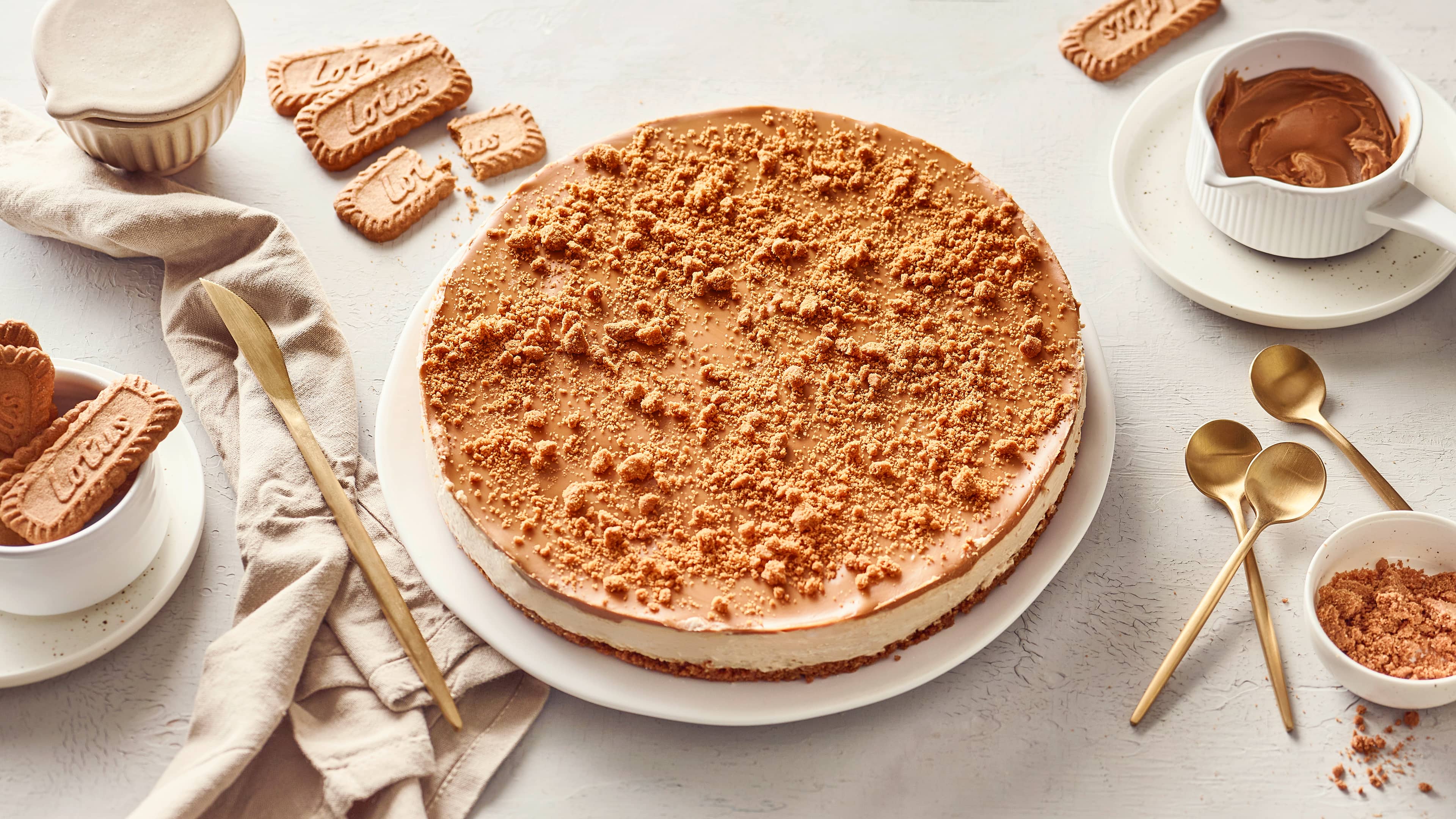 Rezept für Lotus Cheesecake Ein Creme-Kuchen mit einem Keksboden, getoppt mit einer Lotus-Schicht und Kekskrümeln, auf einem runden Teller