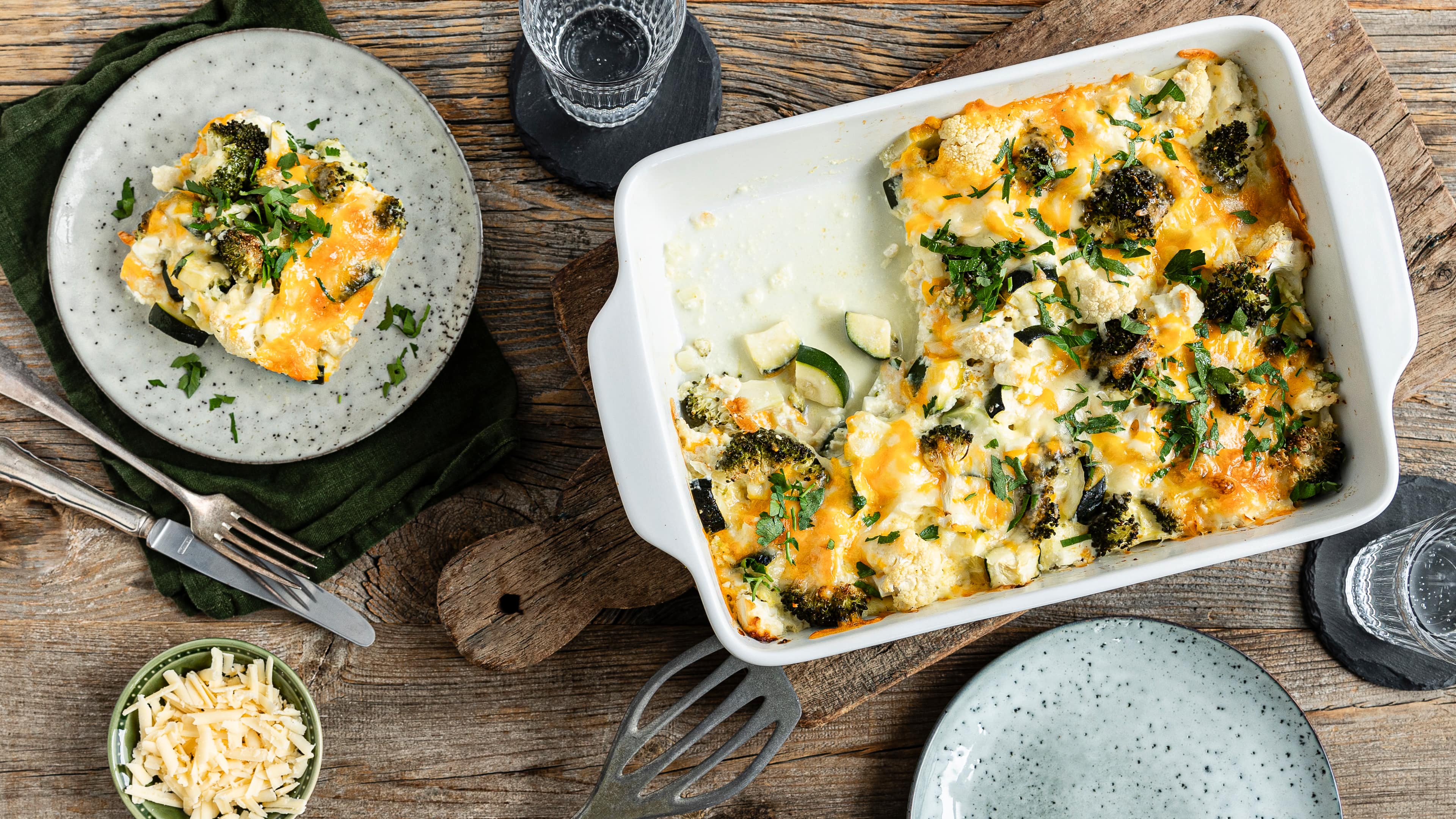 Eine Auflaufform mit überbackenem Brokkoli, Zucchini und Blumenkohl mit Feta, getoppt mit frischer Petersilie