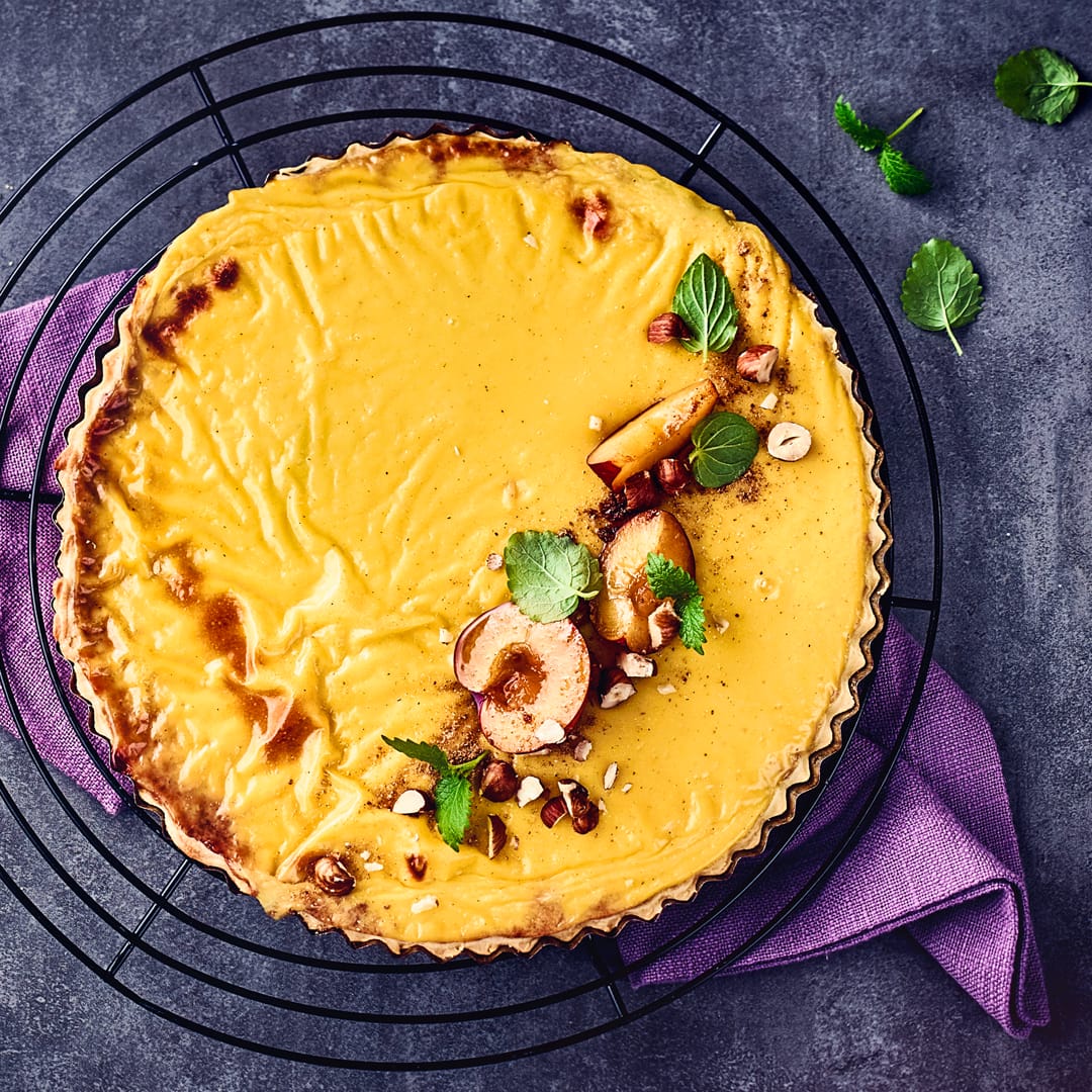 Vanillepudding und Pflaumenkompott machen diese Tarte ganz besonders schmackhaft. Mit Pflaumen, Minze und gehackten Haselnüssen garnieren.