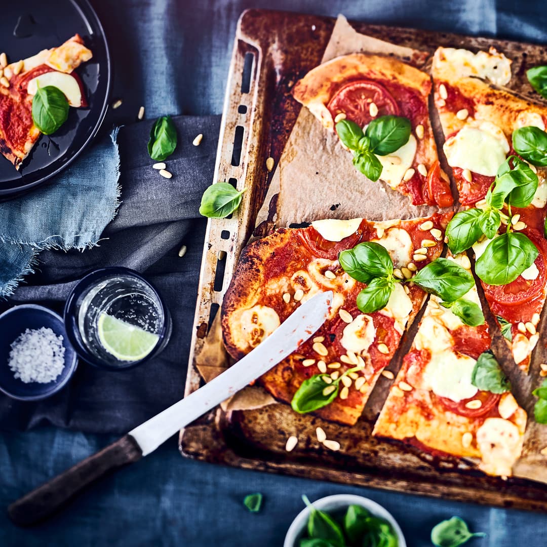 Pizza Caprese, mit selbst gebackenen Pizzateig, frischen Tomaten, Mozzarella und Pinienkernen. Perfekt für einen lauen Sommerabend mit Freunden mit einem feinem Rotwein.