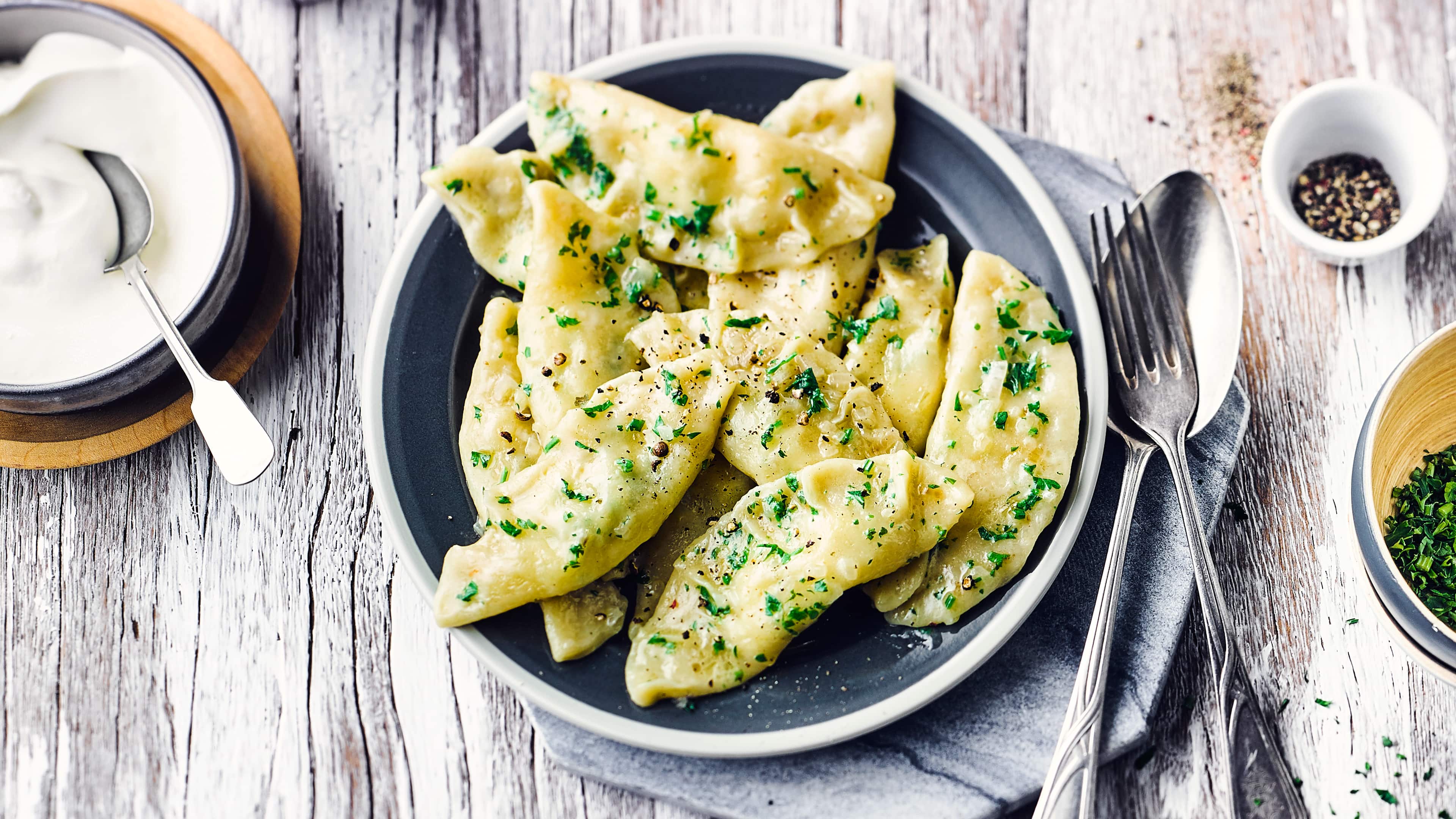 Rezept für polnische Piroggen Ein Teller mit halbkreisförmige Teigtaschen, getoppt mit Petersilie und Pfeffer