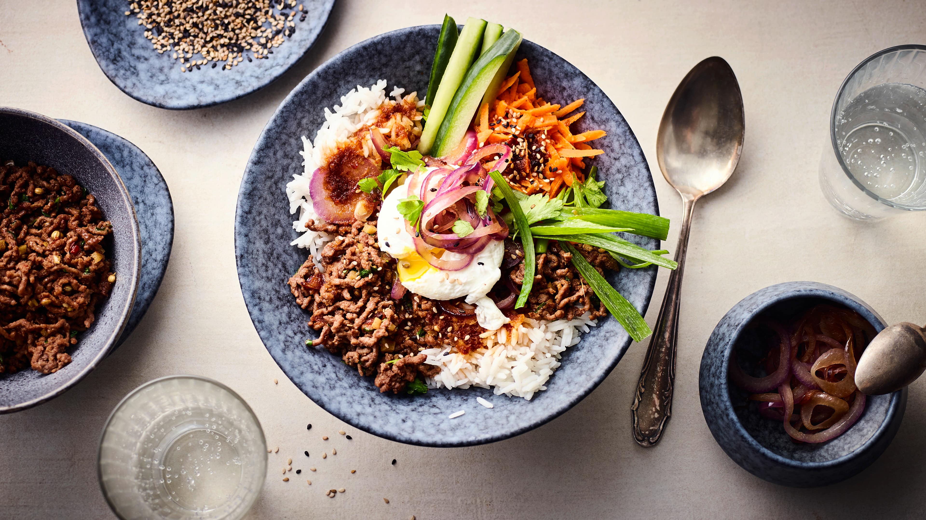 Rezept für Reis Bowl mit Hackfleisch Eine Bowl mit Reis, Hackfleisch, pochierten Eiern, Lauchzwiebeln, Möhren, roten Zwiebel und dunkler Soße