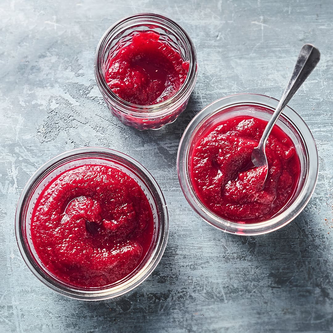 Drei Einmachgläser mit pink-roter Sauce, in einem davon ist ein Teelöffel in die Sauce gedippt