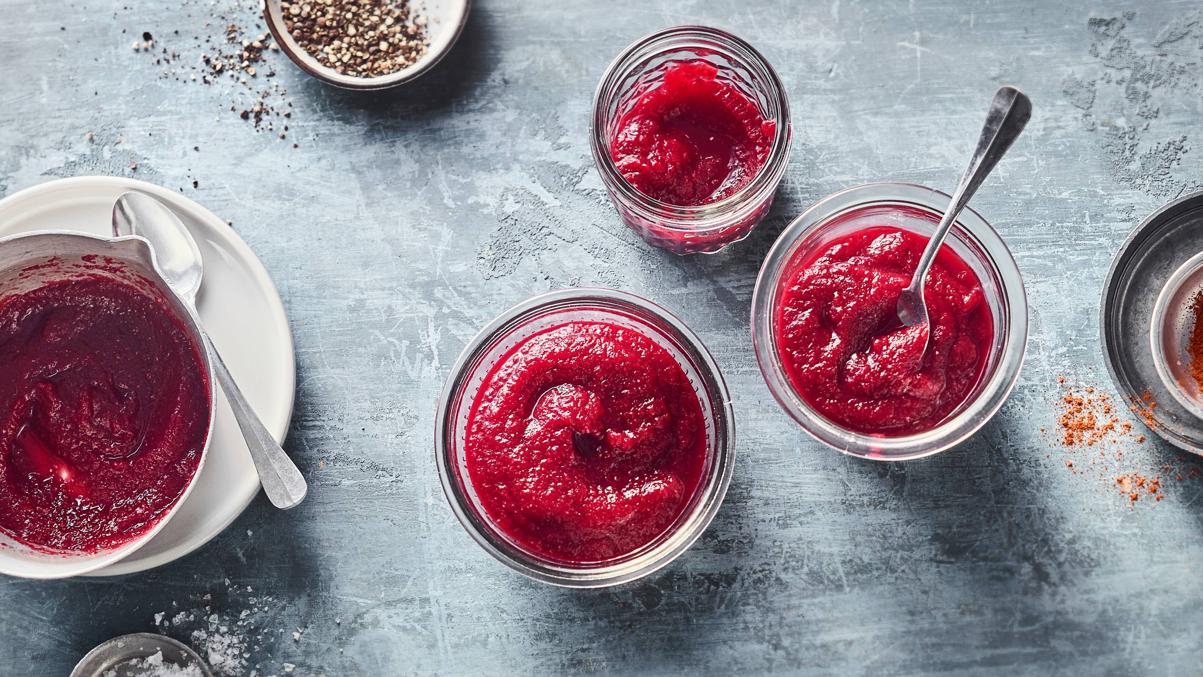 Drei Einmachgläser mit pink-roter Sauce, in einem davon ist ein Teelöffel in die Sauce gedippt