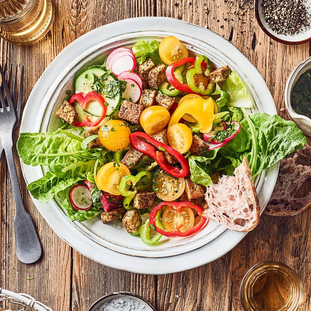 Knackig frische Salatherzen mit Mini-Paprika, Kirschtomaten, Salatgurke, Radieschen und Rucola, als Topping gebratener Kräuter-Tofu.