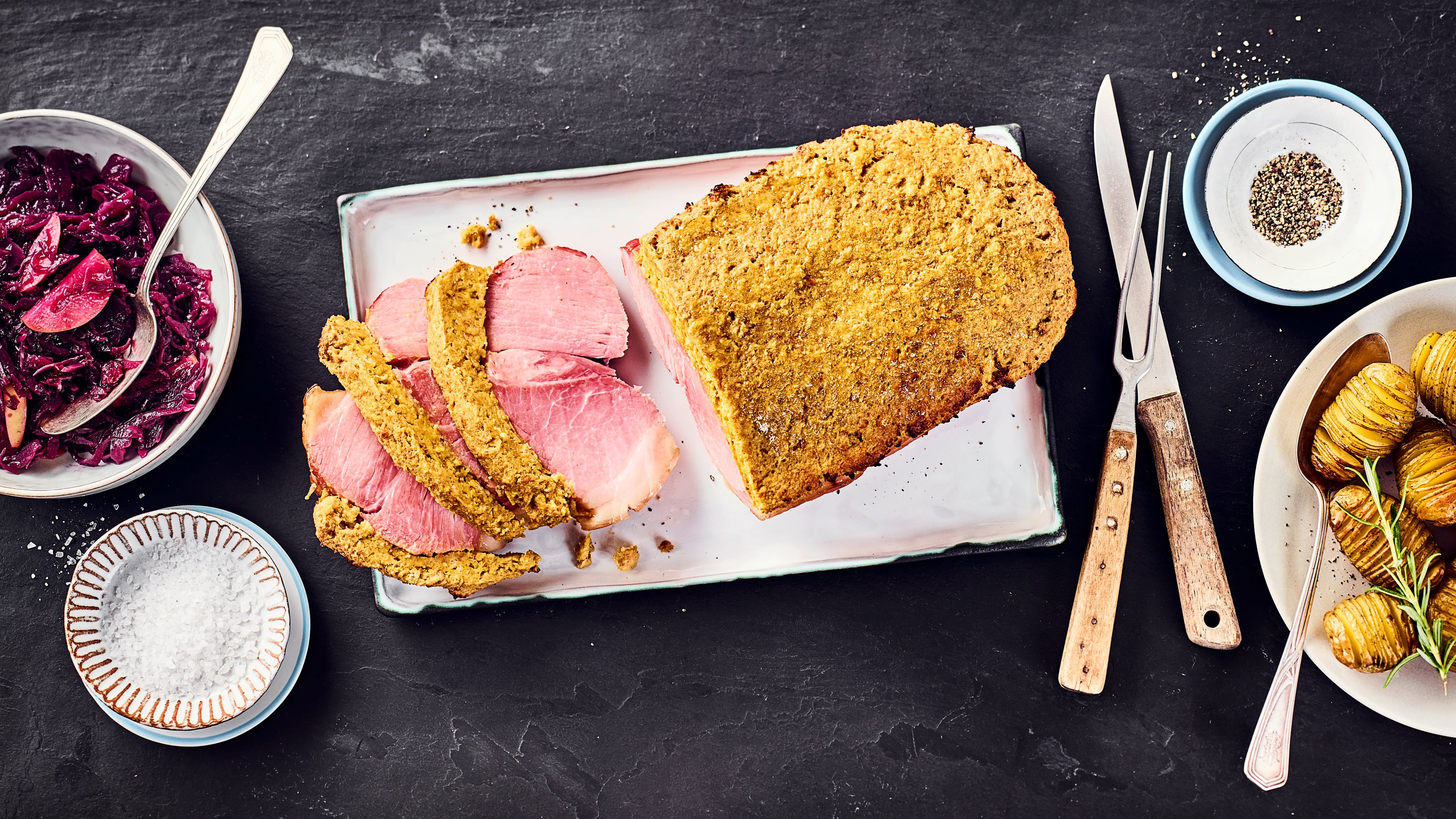 Schinkenbraten Auch als Julschinken oder schwedischer Weihnachtsschinken bekannt: Wir servieren den Schinkenbraten mit Senfkruste, Apfel-Rotkohl und gefächerten Hasselback-Kartoffeln.