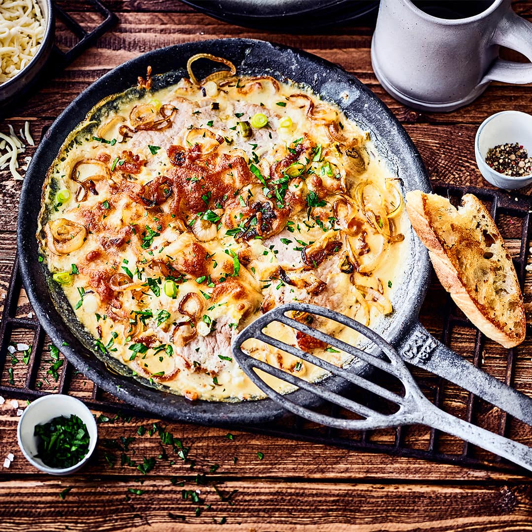Lust auf ein deftiges Fleischgericht? Probieren Sie unser Rezept für Schweineschnitzel in Zwiebel-Sahne-Soße aus: Mit Kräuter Creme fraiche, Knoblauch, geriebenem Käse und einem Schuss Weißwein!