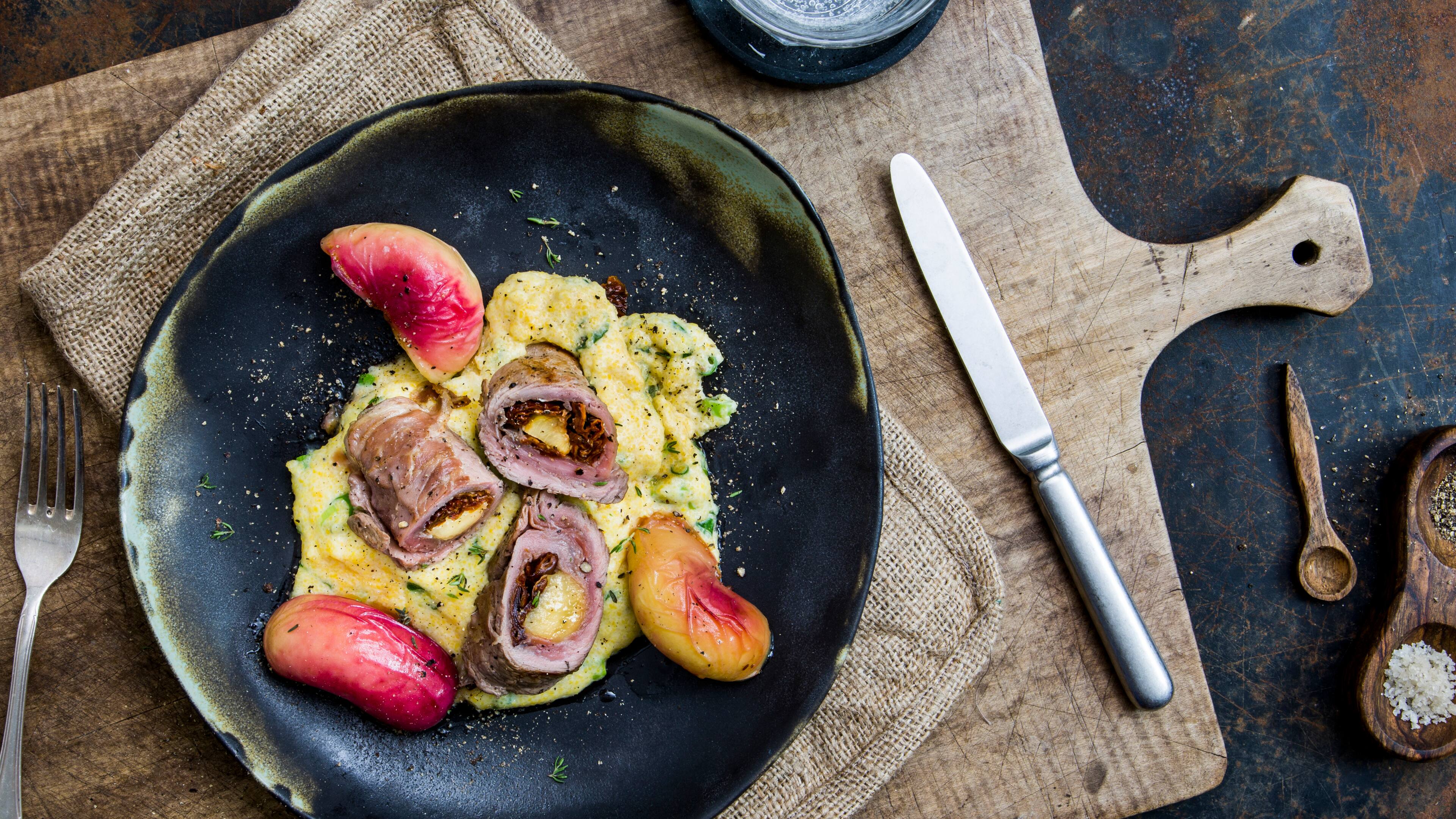 Schnitzelröllchen Italienische Schnitzelröllchen mit Parmaschinken und getrockneten Tomaten. Dazu eine cremige Polenta und marinierte Plattpfirsich-Hälften – einfach köstlich.