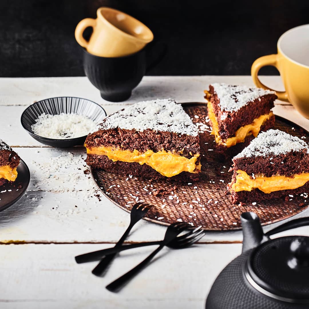 Cremiges Kürbispürree zwischen zwei schokoladigen Kuchenböden getoppt mit köstlichen Kokosraspeln - unser herbstlicher Kürbis-Schoko-Kuchen besticht mit jeder Menge Aromen.