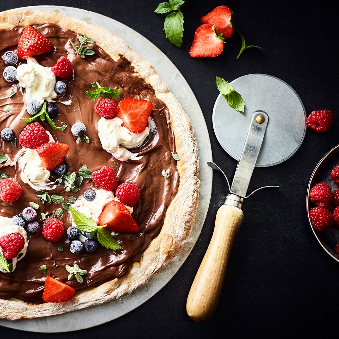 Pizza als Nachtisch – das geht! Mit diesem Rezept gelingt Ihnen eine sündhaft leckere Schokoladenpizza mit frischen Beeren und Minze.