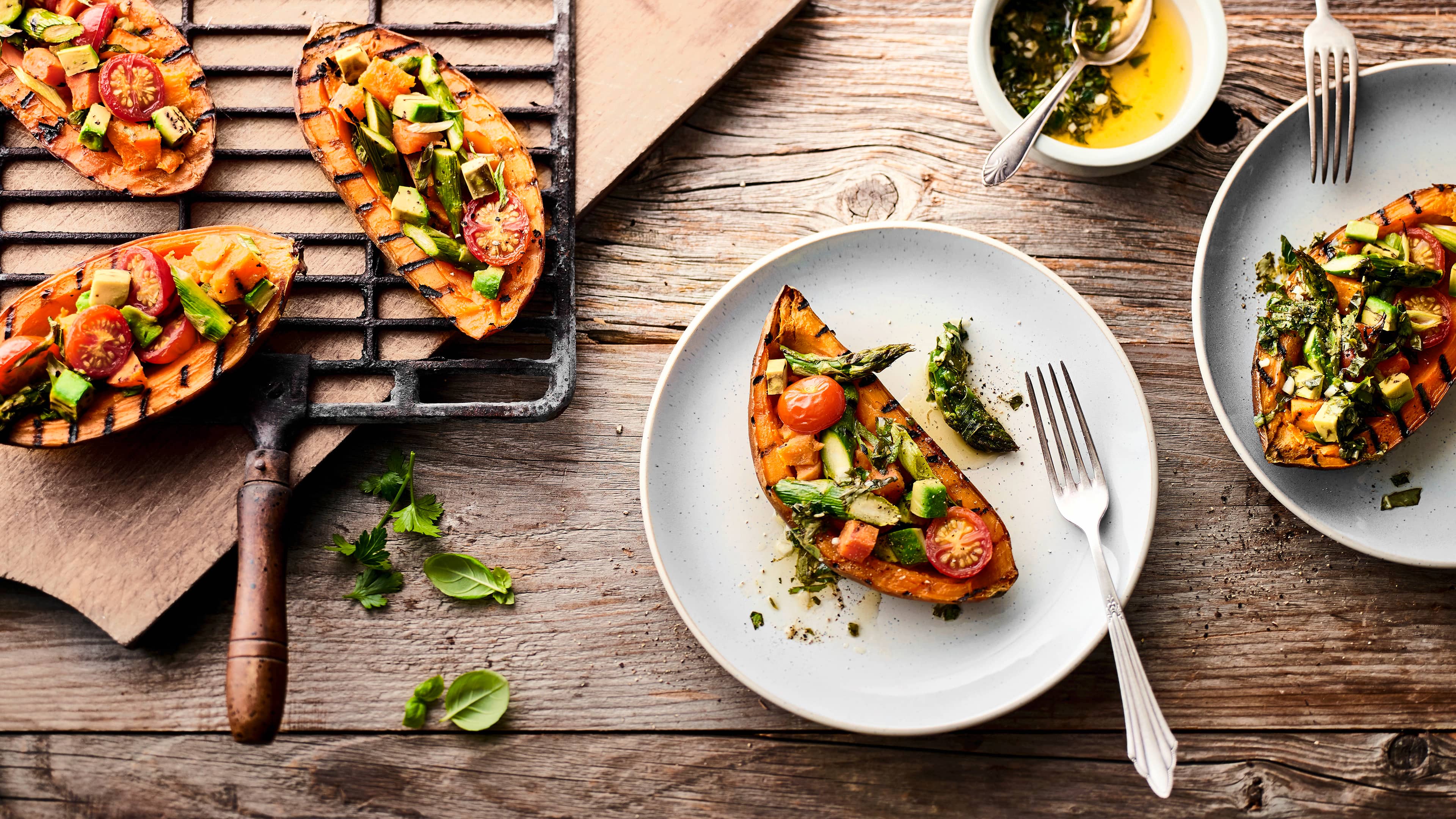 Eine fantastische Beilage, die Sie so vielleicht noch nicht probiert haben: Süßkartoffel vom Grill mit Tomaten-Avocado-Spargel-Topping und selbstgemachter Kräutersoße.
