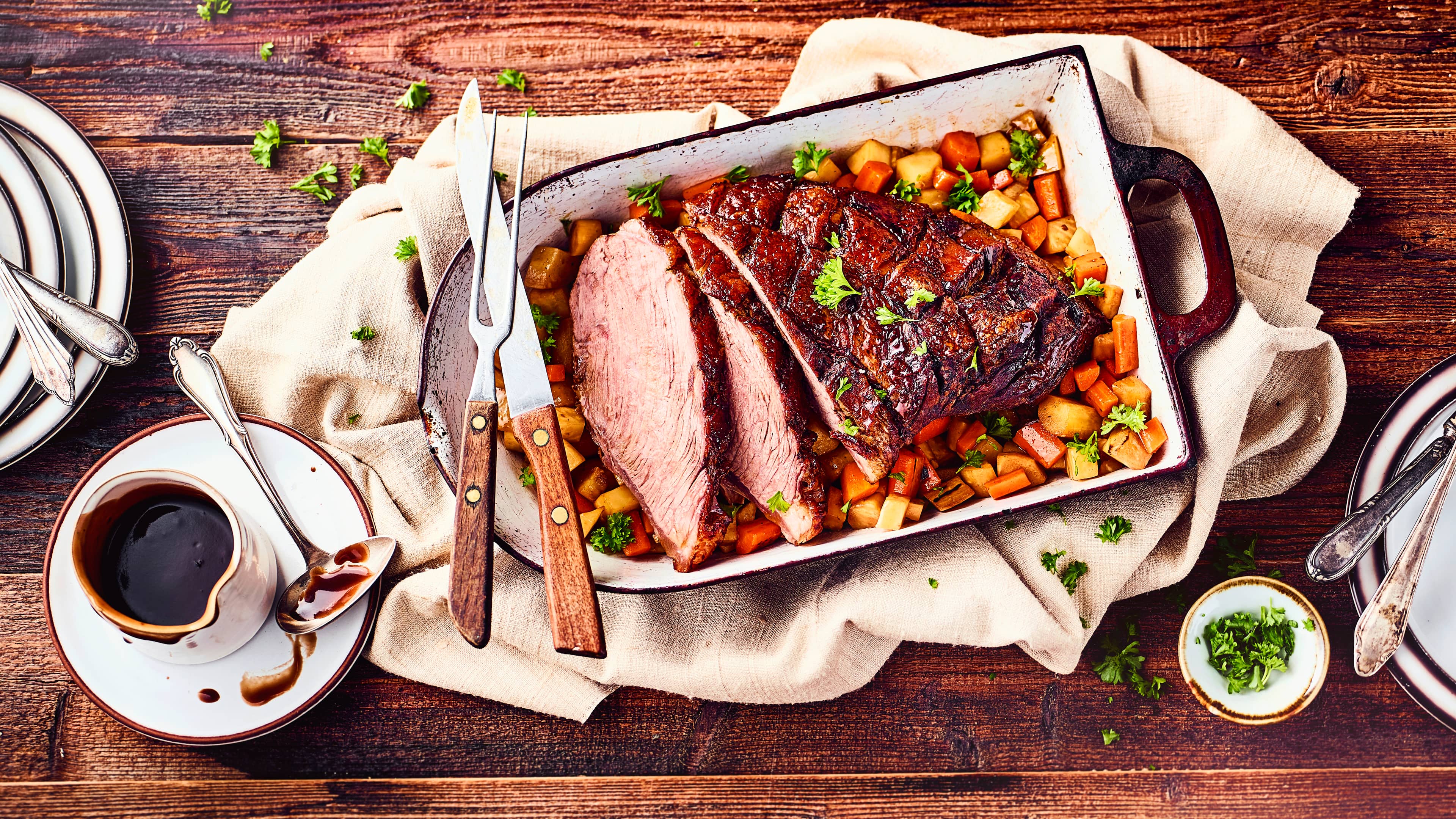 Rezept für Tafelspitz Braten Eine rustikale Auflaufform mit einem großen Stück saftigem Fleisch mit einer knusprigen Kruste und Ofengemüse