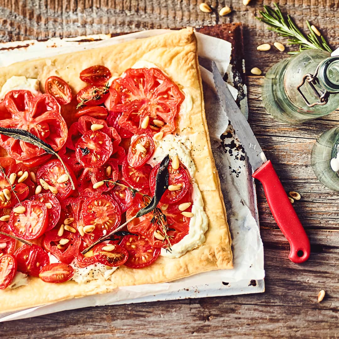 Leichtes Sommergericht vom Blech: Probieren Sie unsere Tomaten-Pinien-Tarte mit Ricotta und Zitronenthymian – vegetarisch und mediterran!