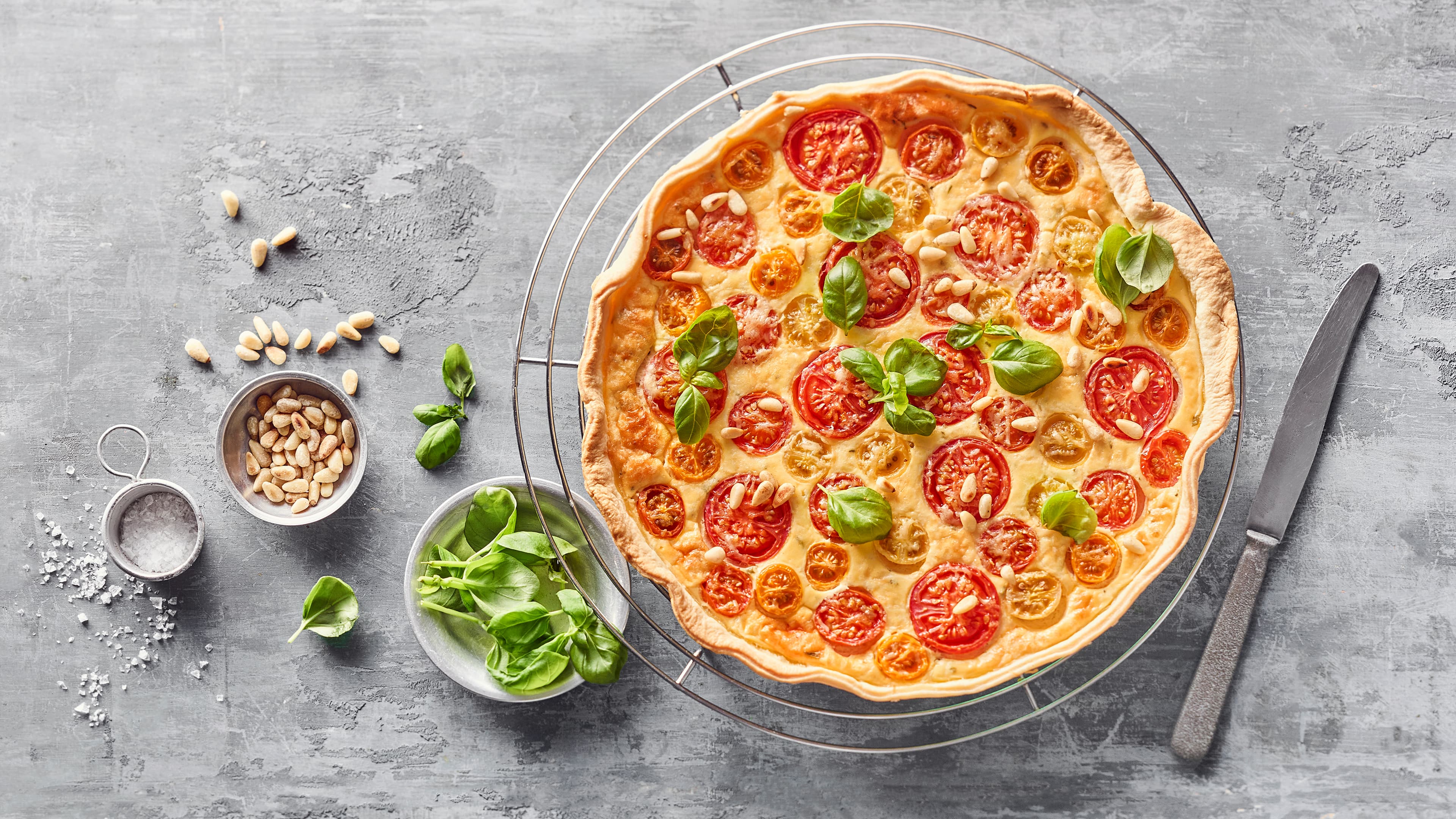 Rezept für Tomatenkuchen mit Ricotta Kuchen aus einem Blätterteigboden, einer Ricottafüllung und kleinen Tomaten, garniert mit gerösteten Pinienkernen