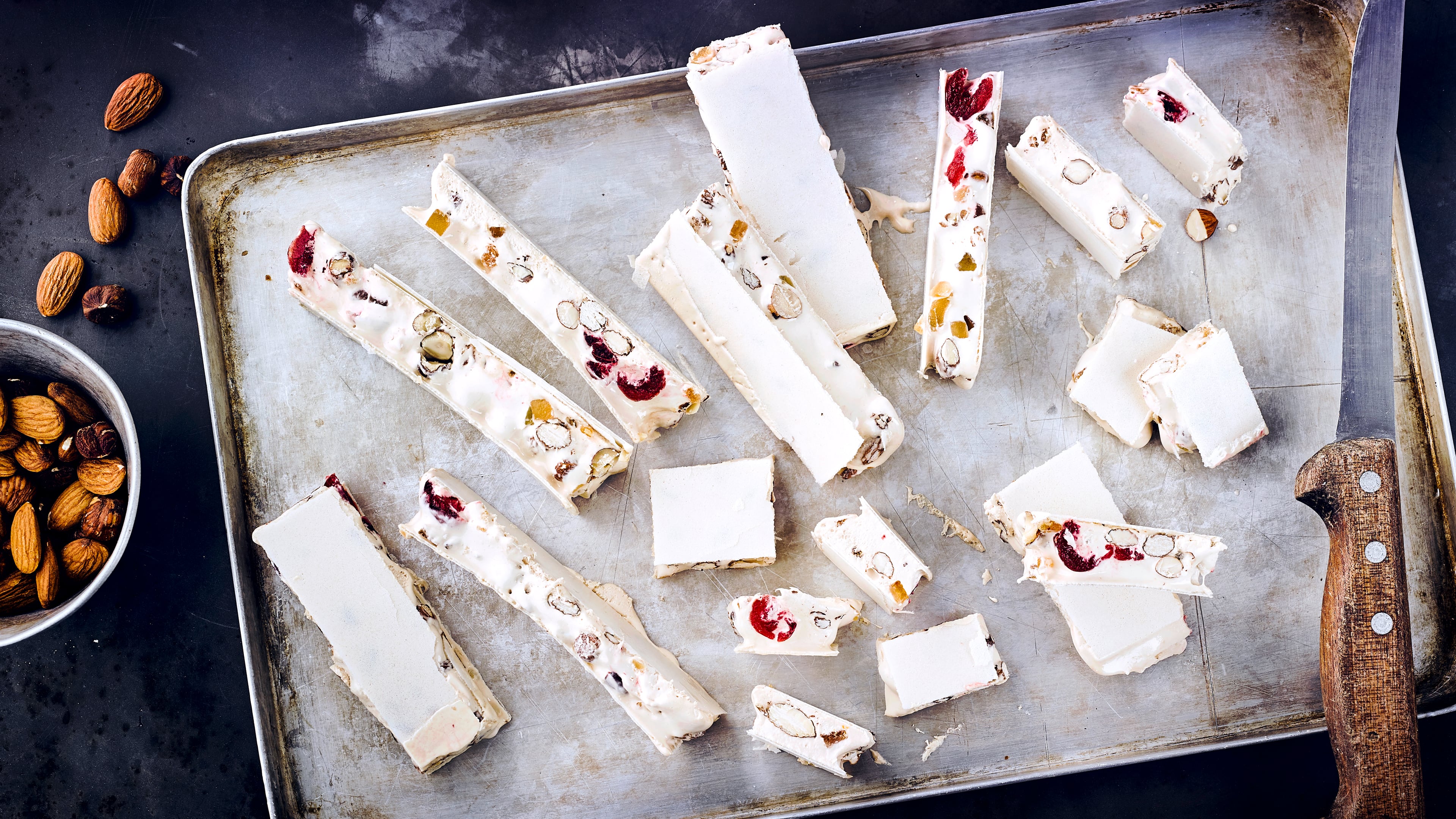 Nougat-Rezept für türkischen Honig Ein Blech mit länglichen Nougatstücken mit Nüssen, kandierten Fruchtstückchen und Backoblaten