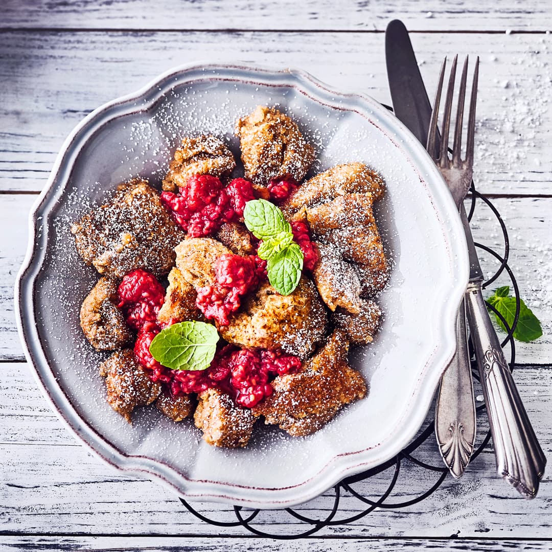 Köstlicher veganer Kaiserschmarrn mit Puderzucker und heißem selbstgemachtem Himbeerkompott ist nicht nur ein kleines Highlight des Tages.